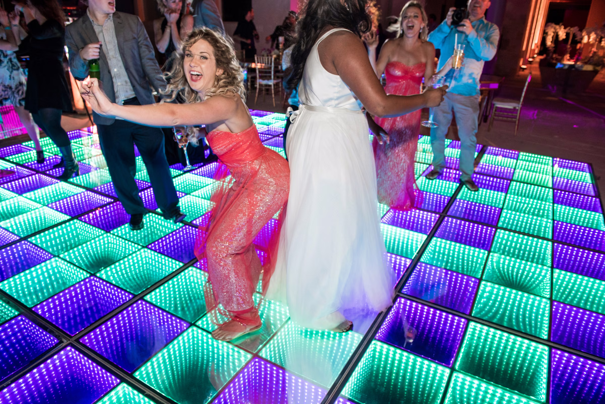Avanti dances with guests on a brightly illuminated multicolored dance floor