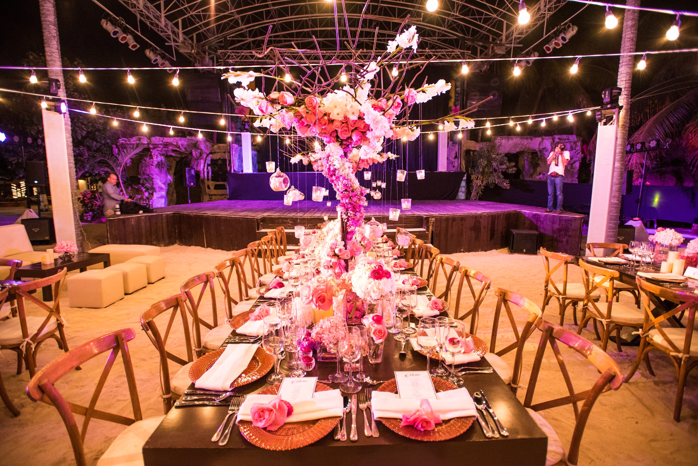 The welcome dinner head table leads toward a stage beneath overhead lights