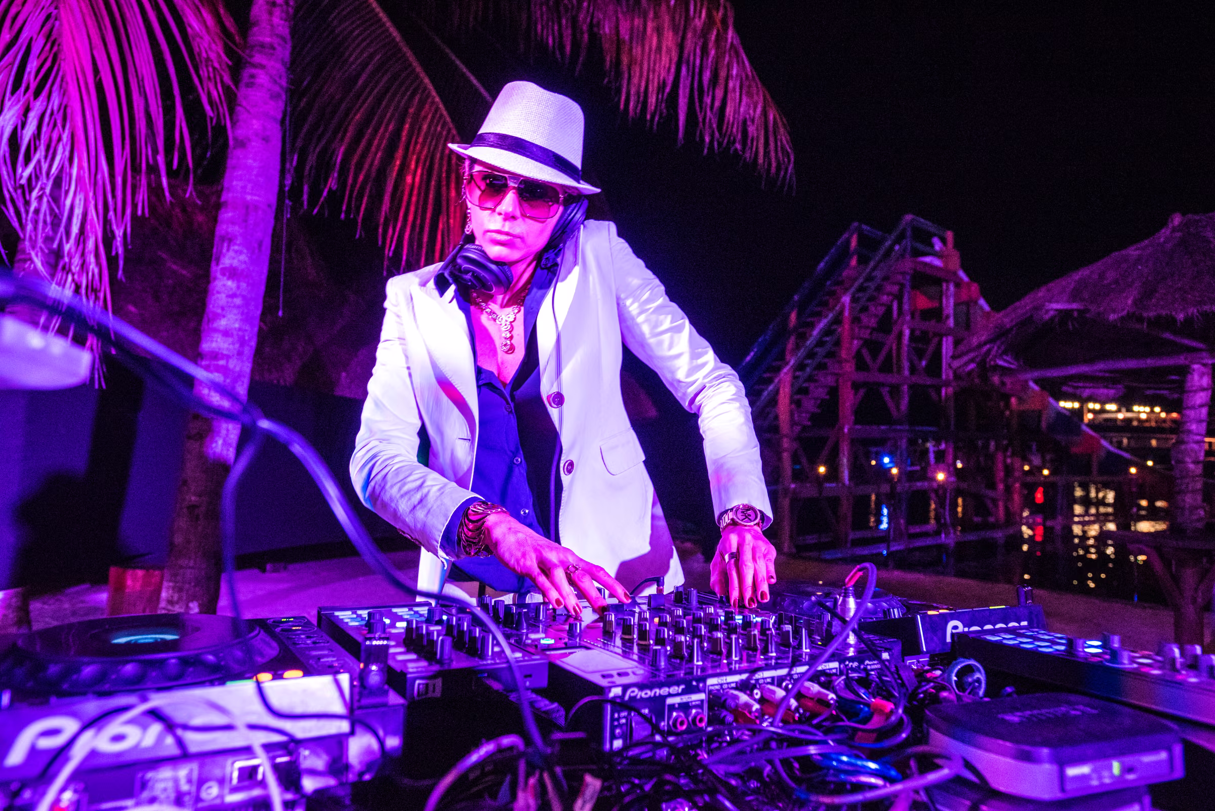 The DJ works at the mixing equipment beneath purple light