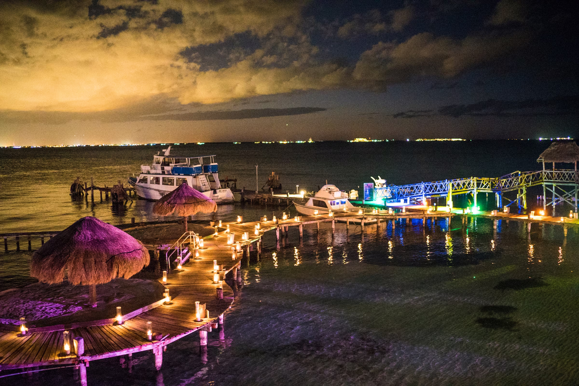 Illuminated docks and boats stretch out over the water beneath an evening sky