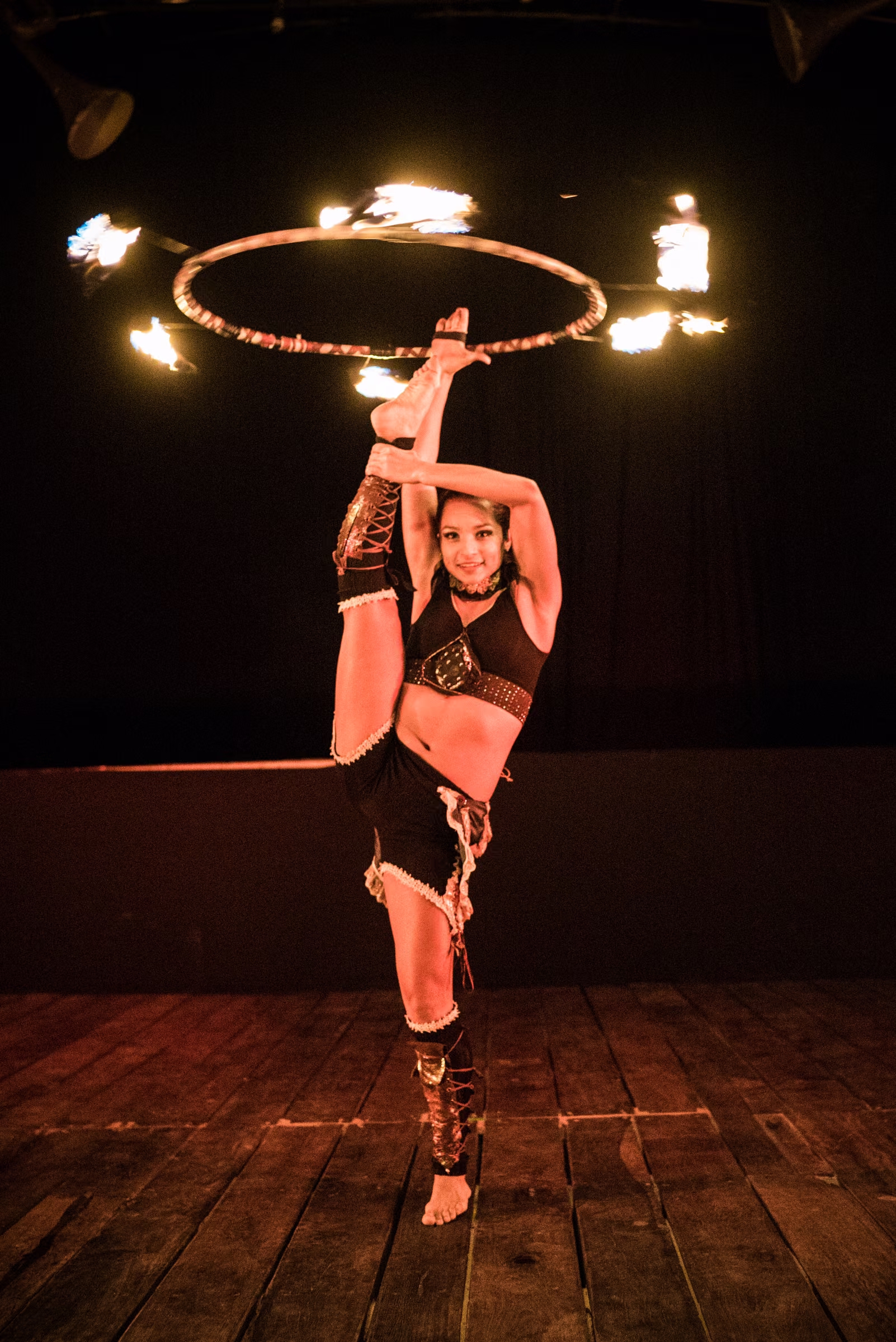 A performer balances with a flaming hoop raised overhead