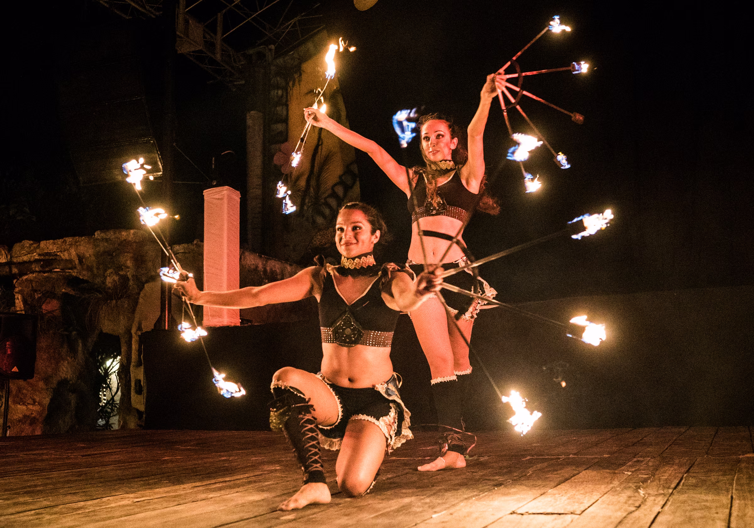Two fire performers pose together with flames extended around them
