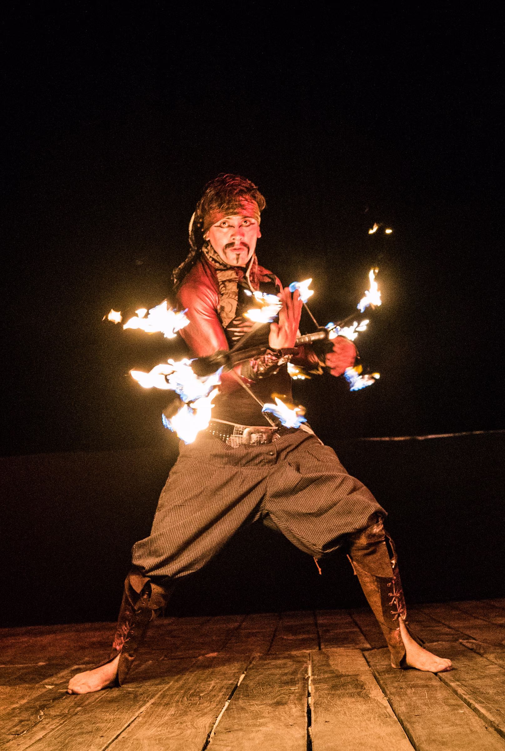 A fire performer moves across the stage with several small flames