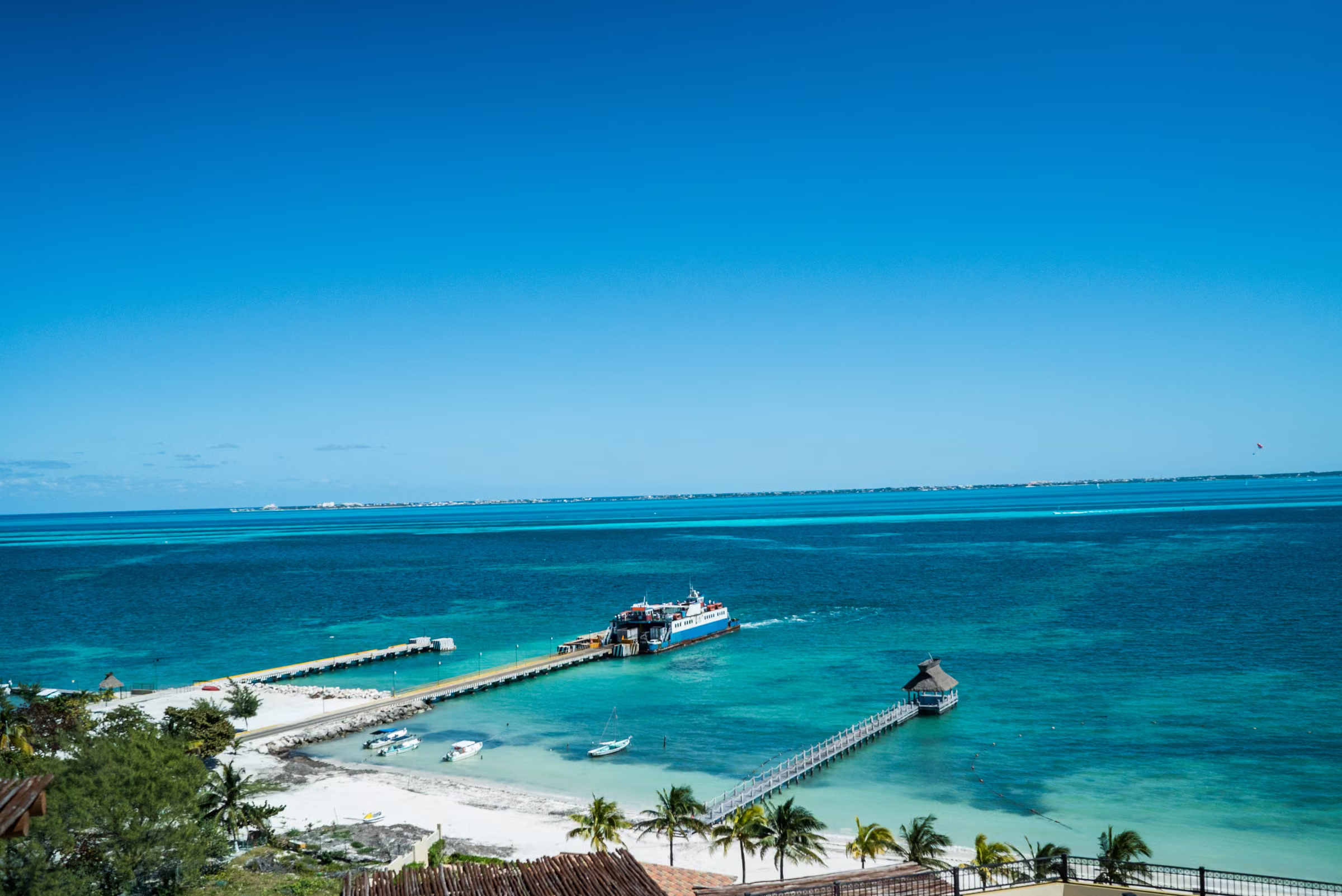Blue water, a beach, and a pier are seen from the couple’s suite