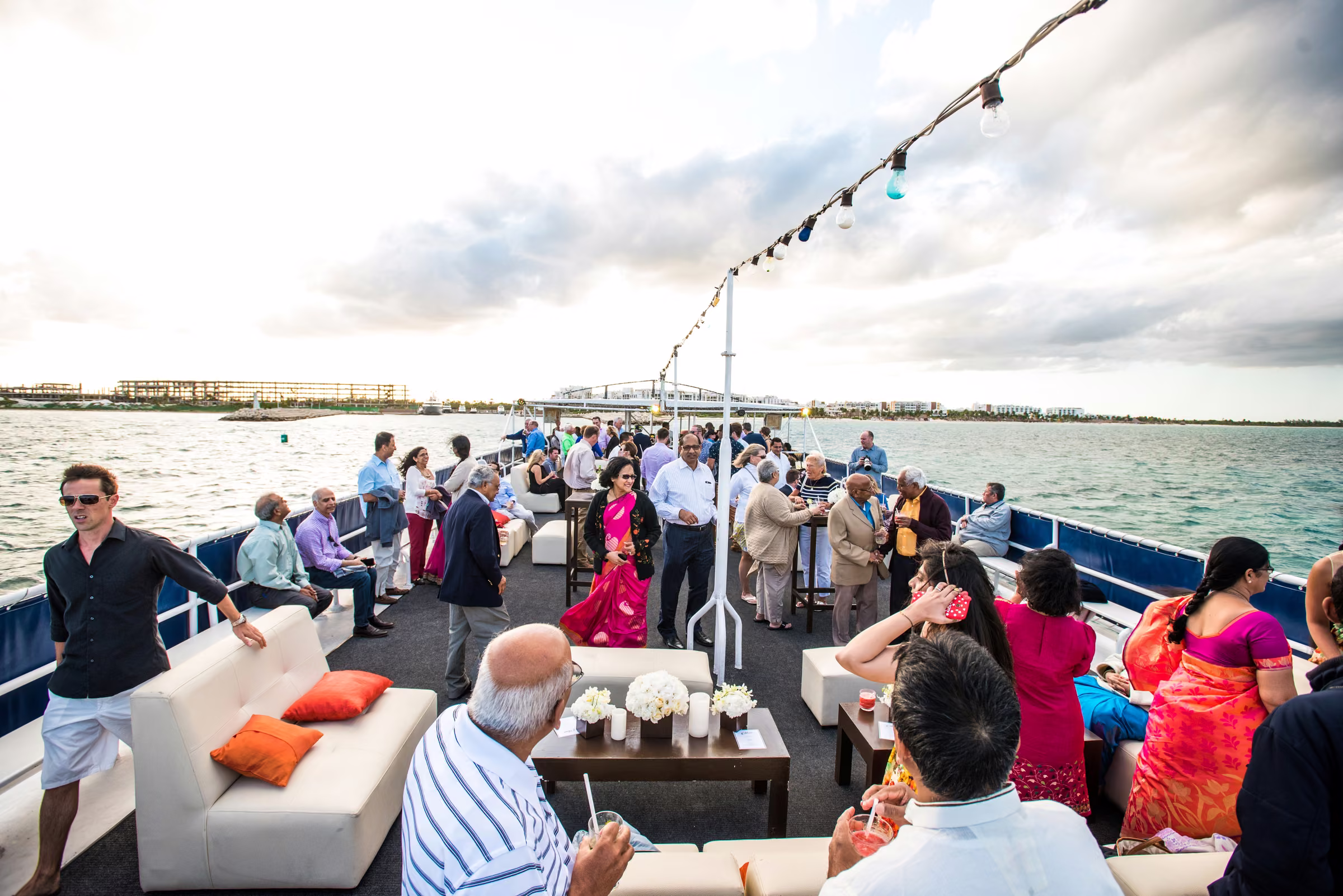Wedding guests gather on the open deck of the boat for cocktails