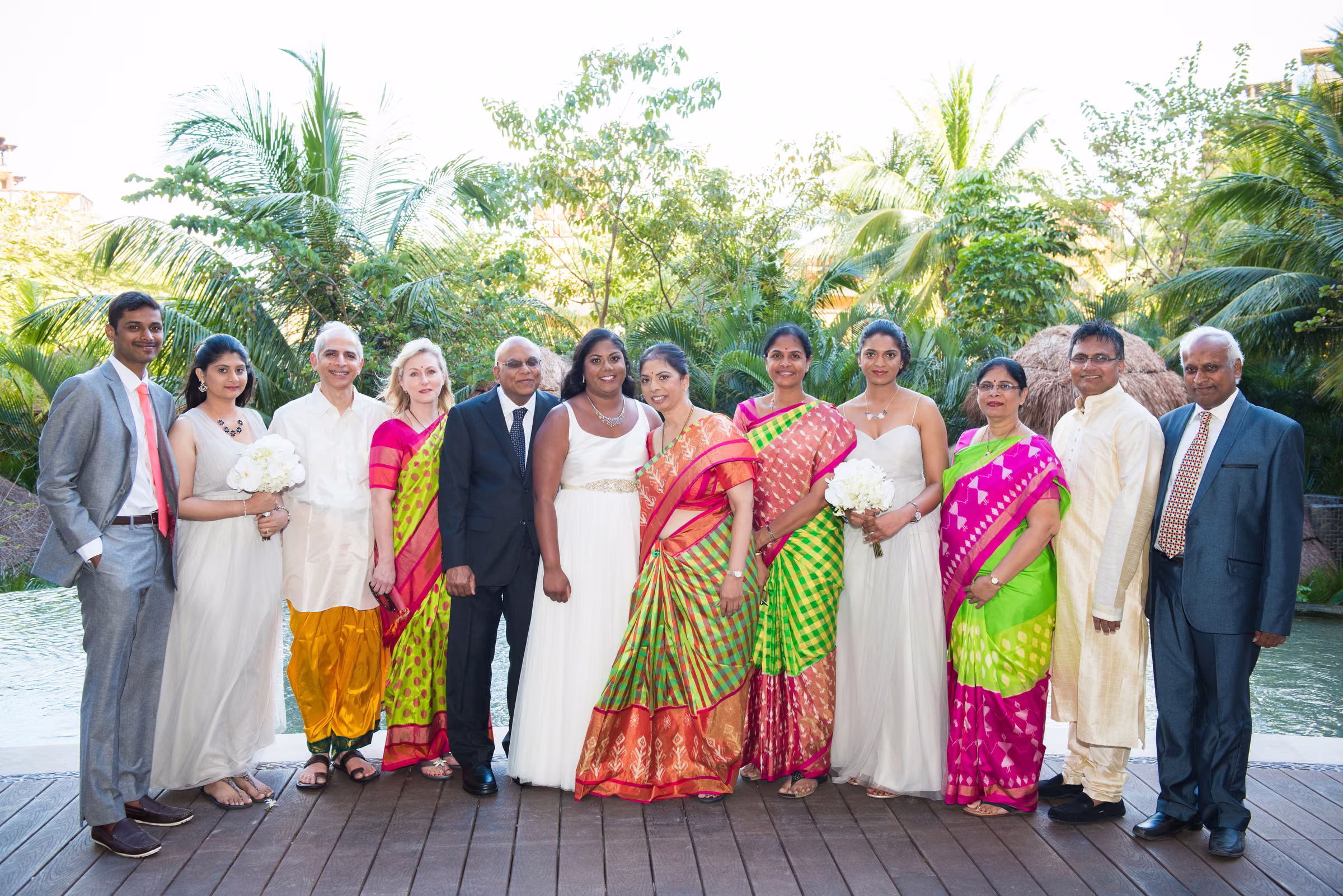 Avanti and Tony stand with the bride’s family among palms and greenery