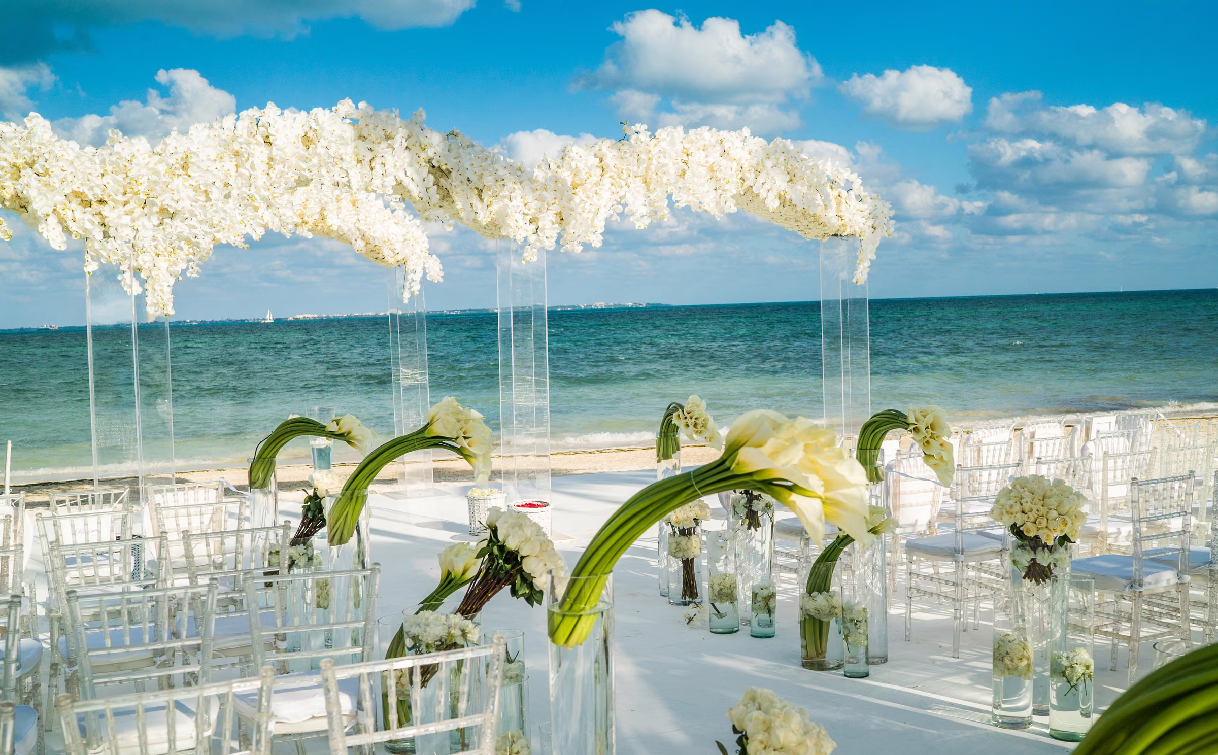 White flowers frame a beach ceremony canopy with the ocean beyond