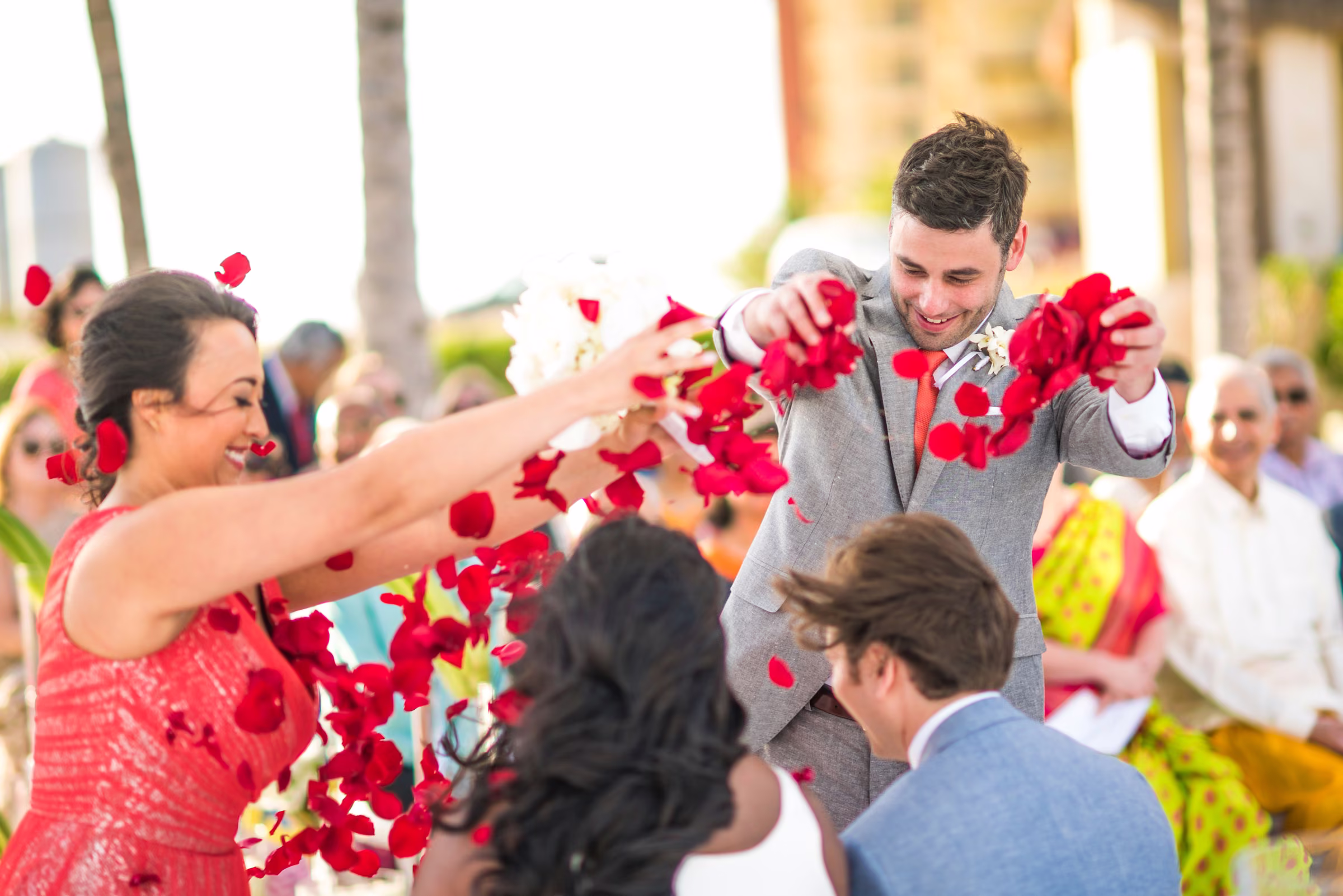 Guests scatter red rose petals over Avanti and Tony during their beach ceremony