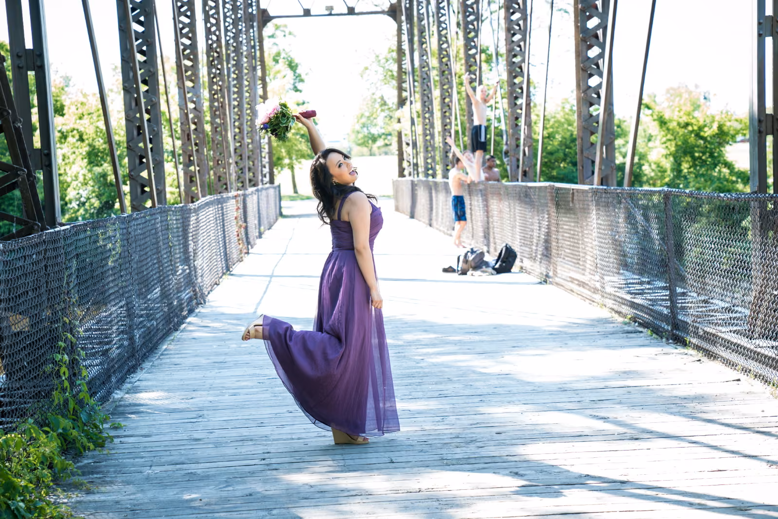 A bridesmaid in a purple dress turns on a steel pedestrian bridge in downtown Minneapolis