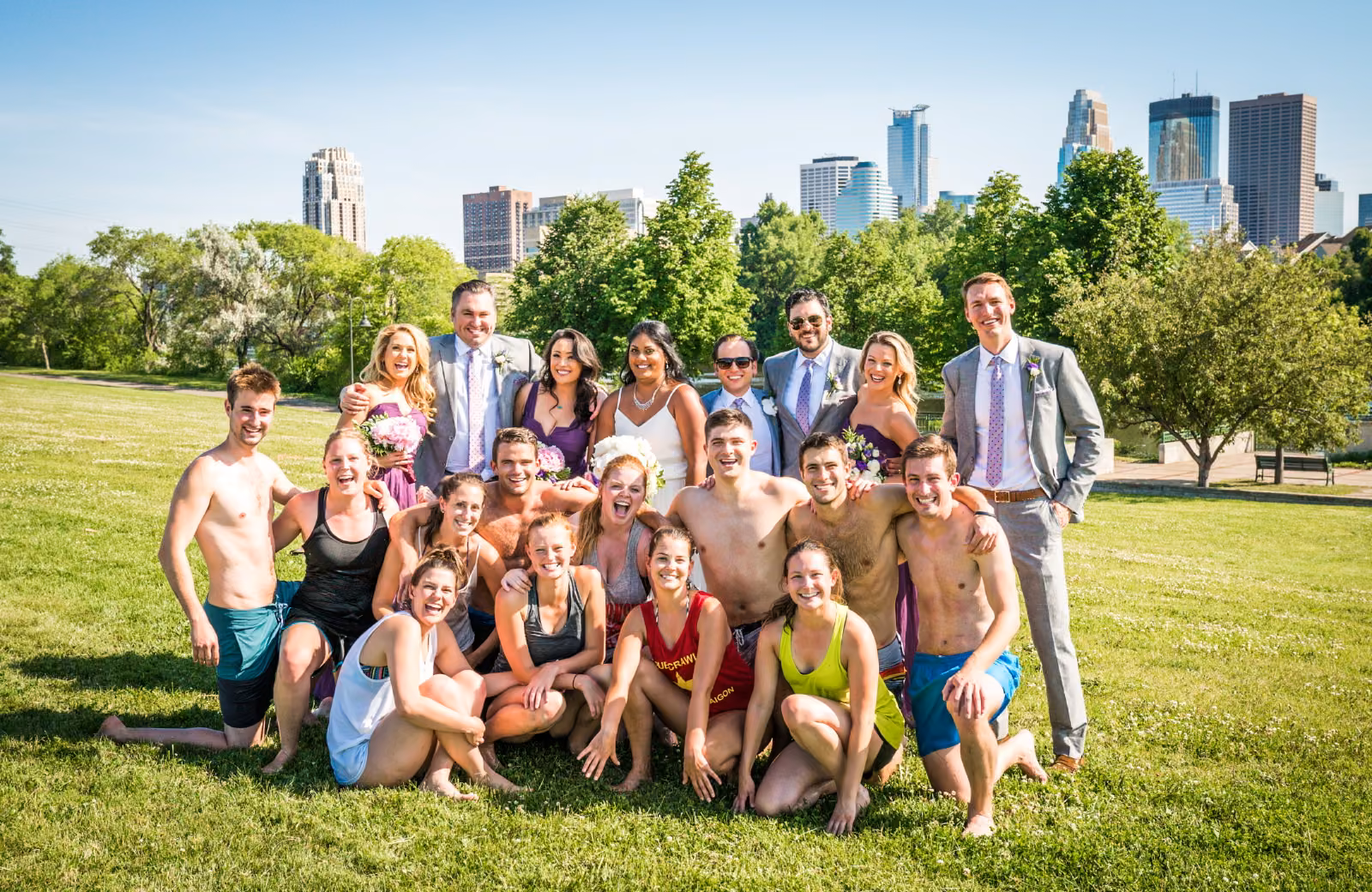 Avanti and Tony and their wedding party pose with the slip-and-slide group on a sunny lawn beneath the Minneapolis skyline