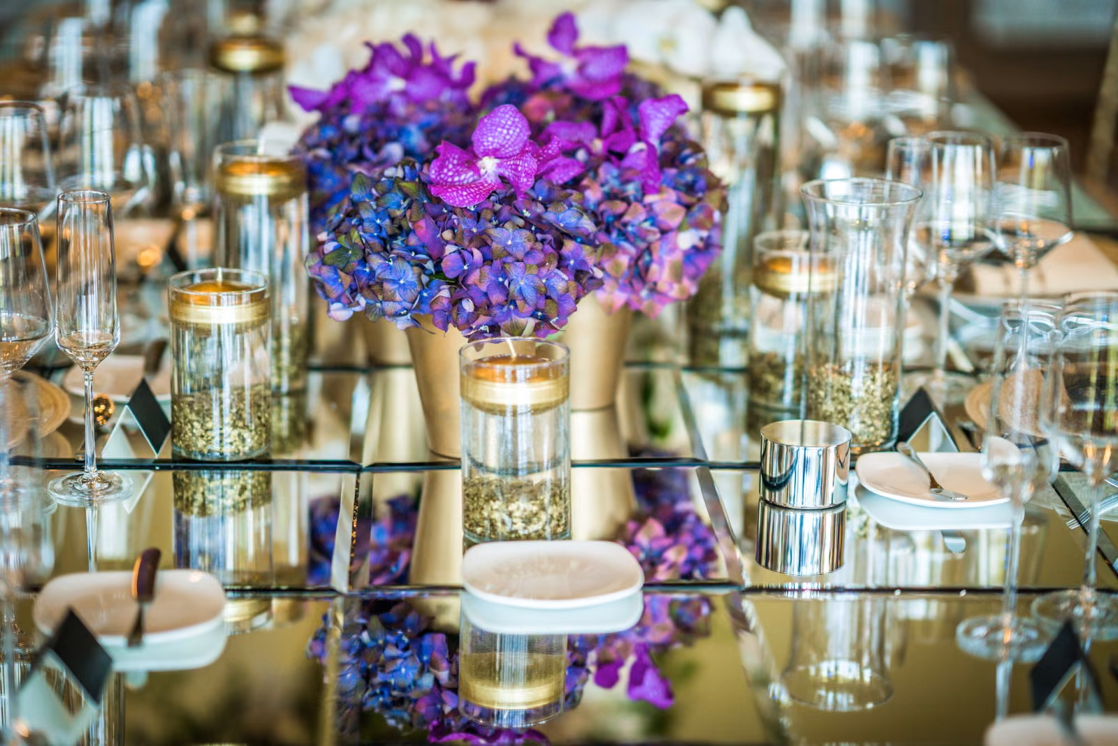 Gold-rimmed glassware and a purple floral centerpiece fill a reception table at Interlachen Country Club
