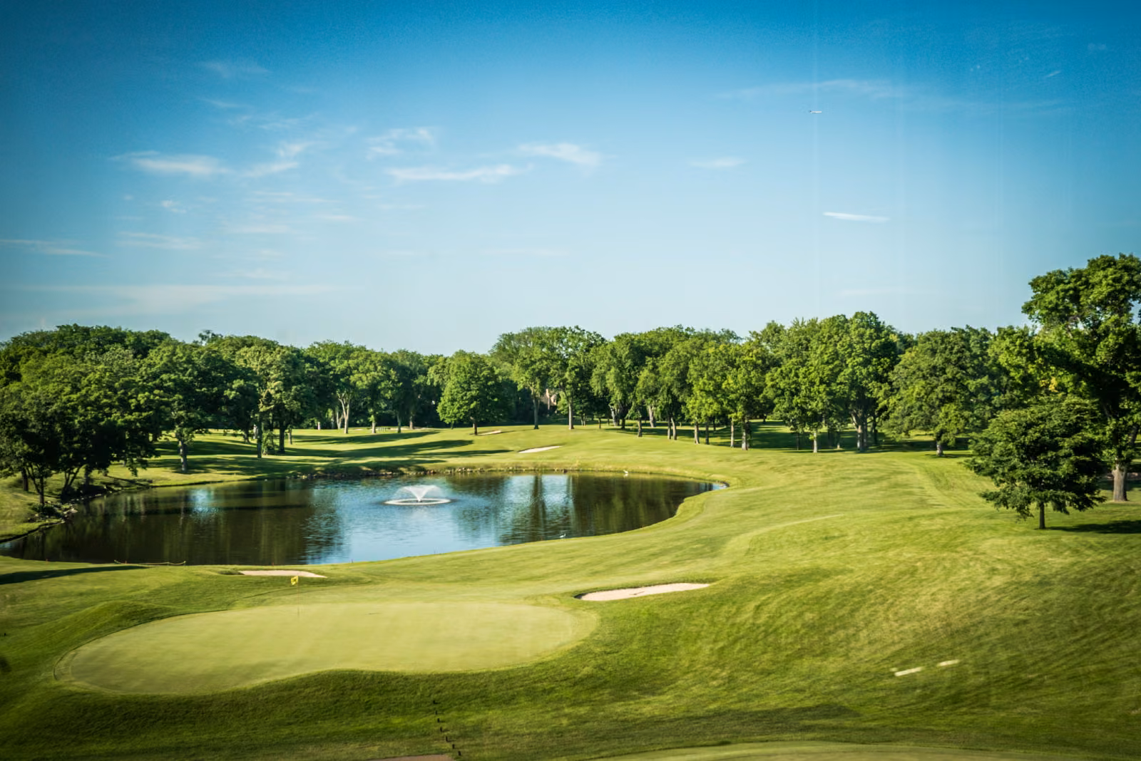 The green golf course and a pond at Interlachen Country Club viewed from near the ballroom