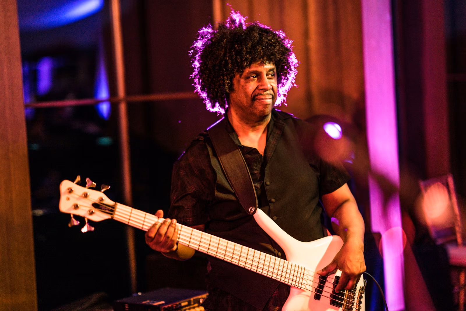 A bass guitarist performs under colorful stage lighting during the wedding reception at Interlachen Country Club