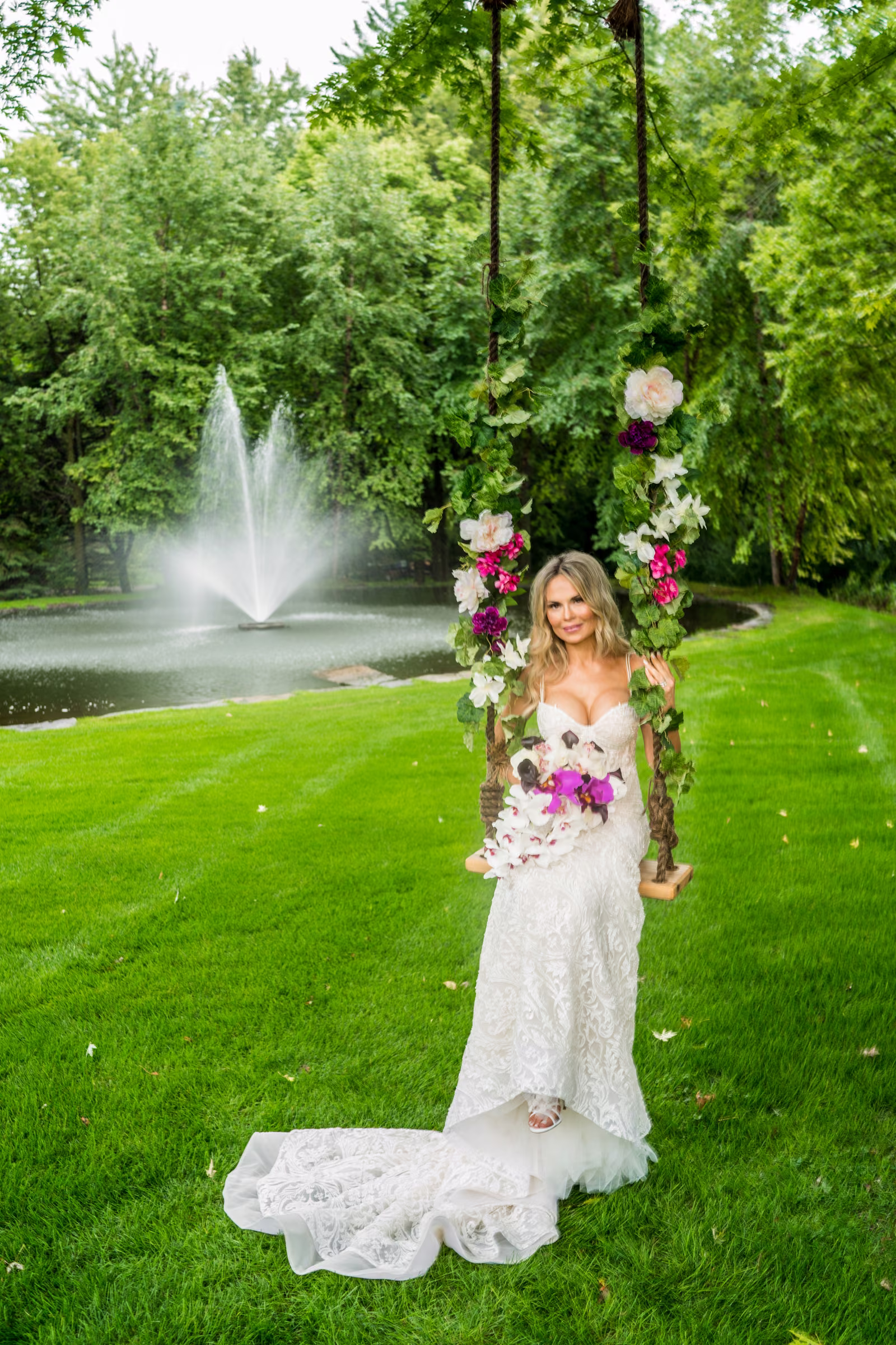 Daiva sits on a flower-decorated swing beside a pond and fountain