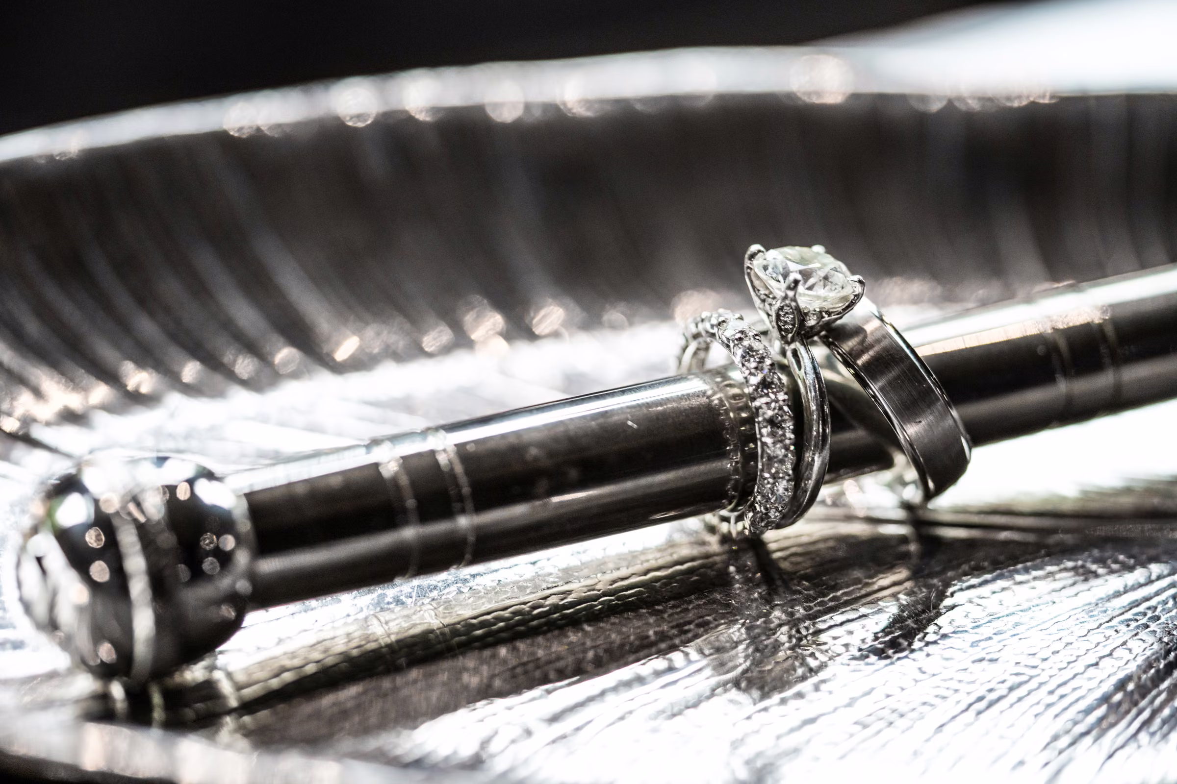 Diamond wedding jewelry rests against a reflective decorative silver surface