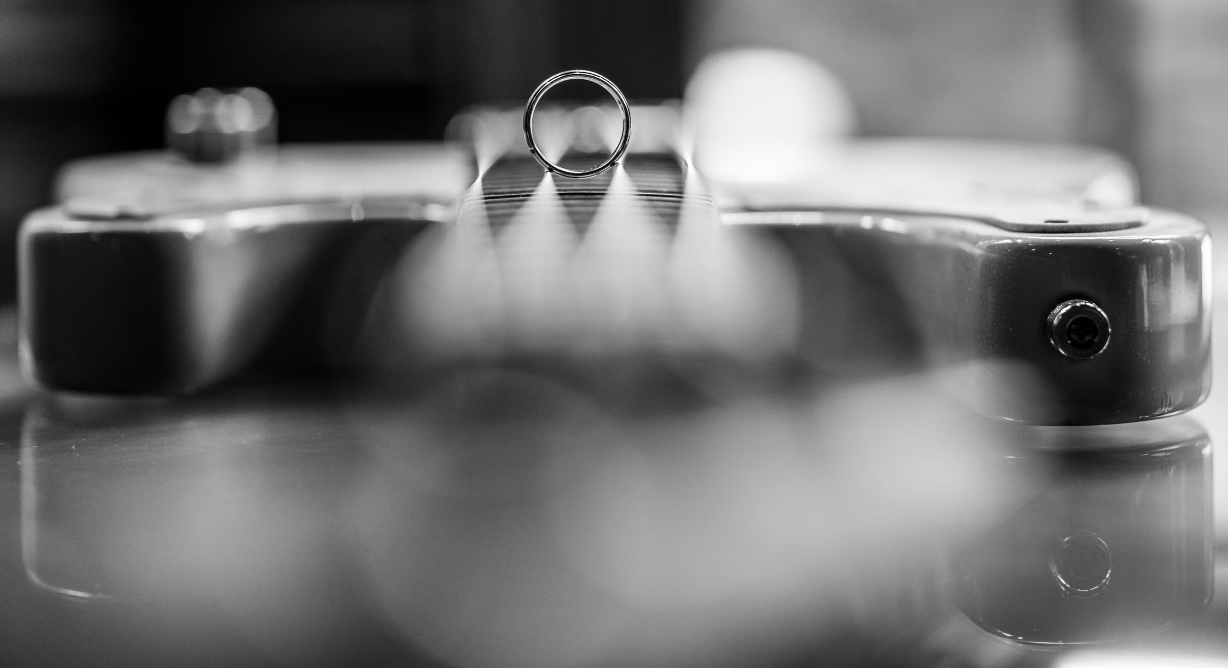 Bill’s wedding band stands on the strings of a bass guitar in a black and white close-up
