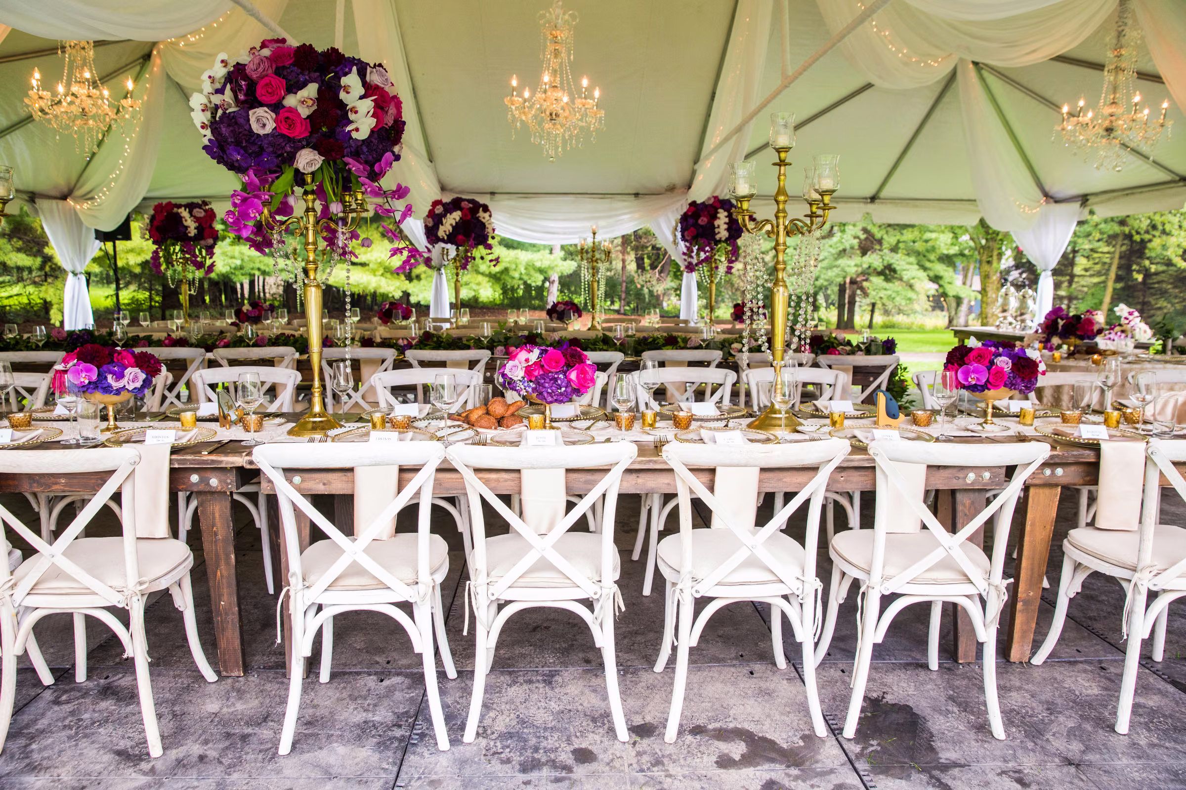 A side view shows white chairs, colorful flowers, and chandeliers beneath the reception tent