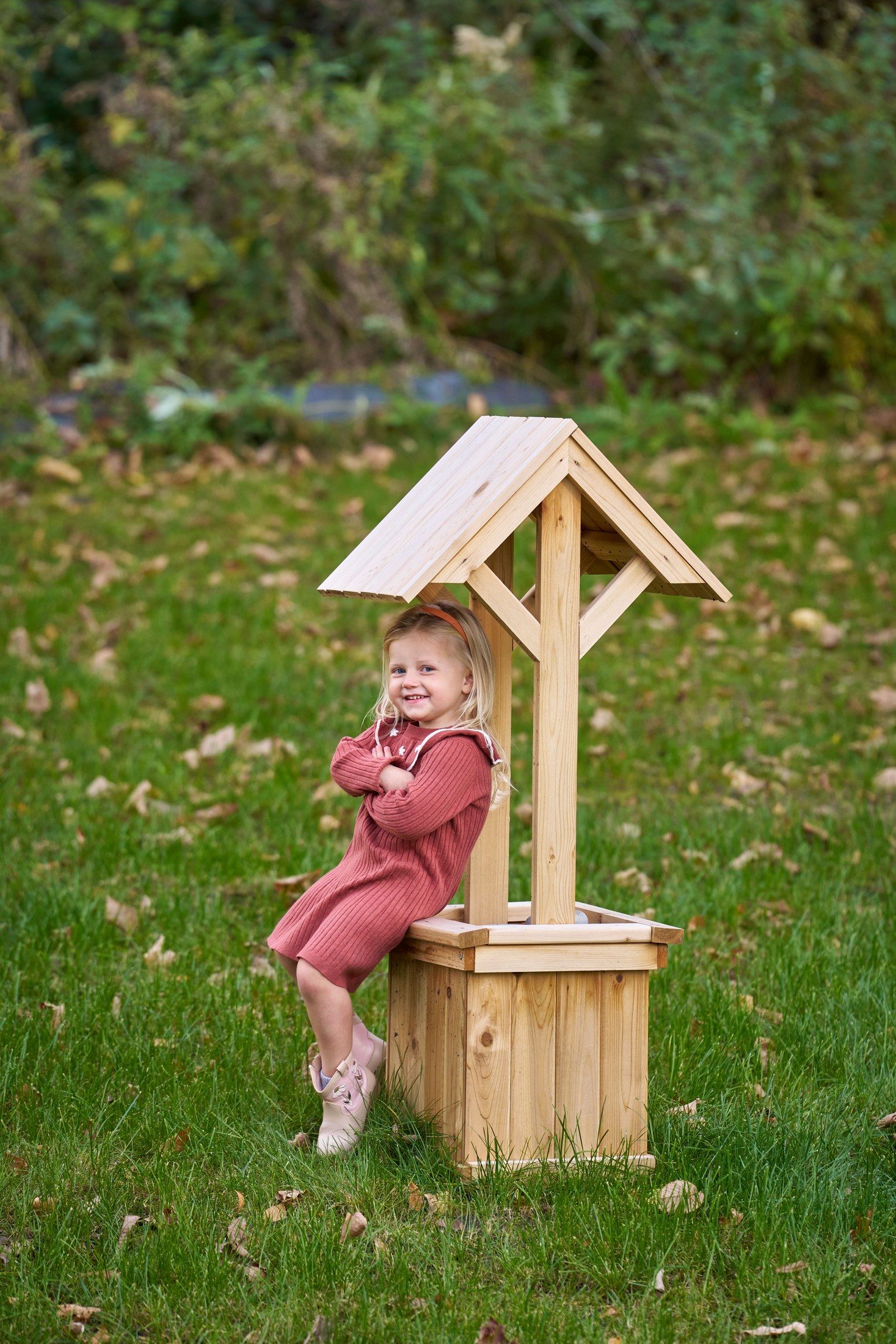 The Engles’ daughter leaning against a small wooden wishing well in their Orono, Minnesota backyard
