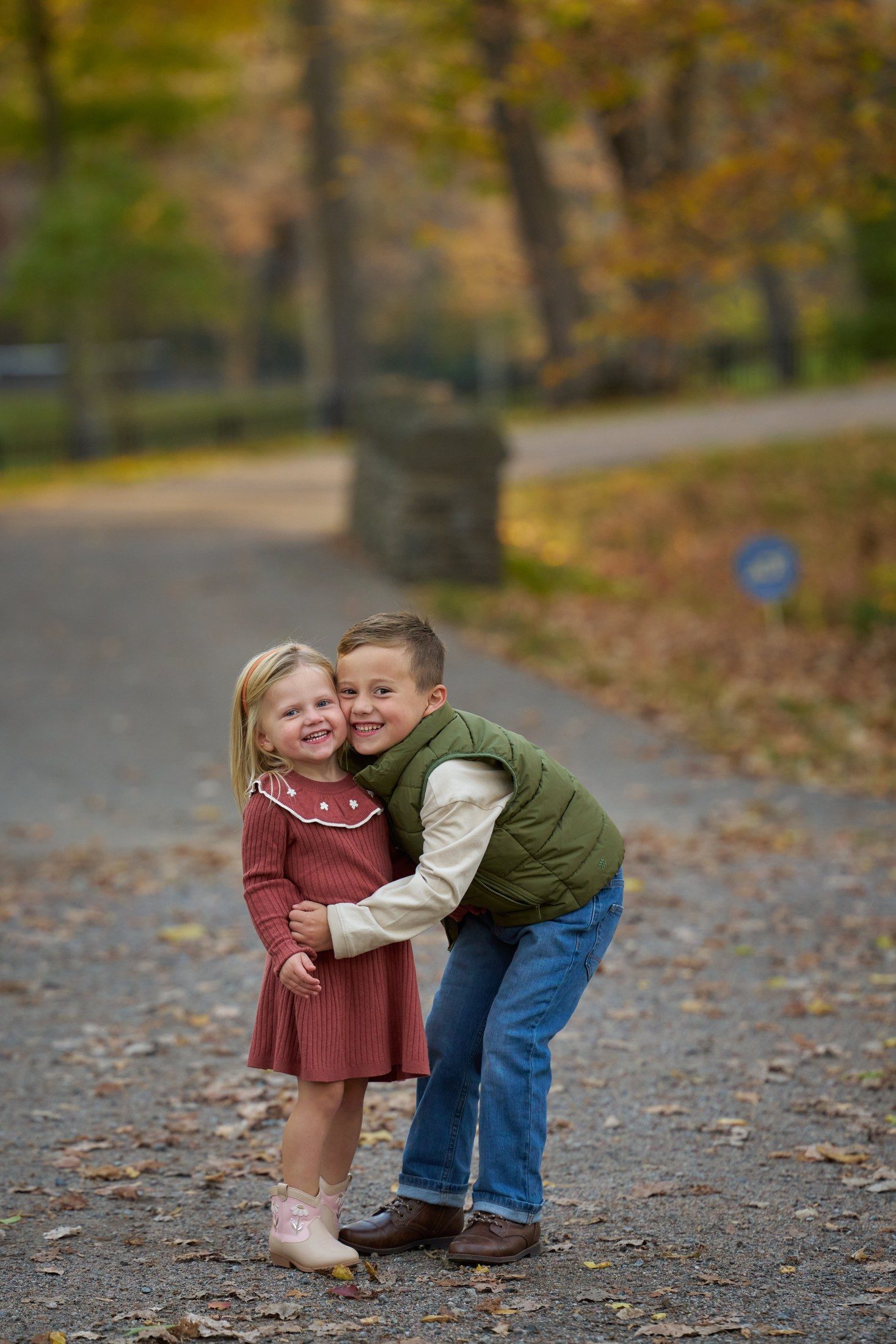 Brother and sister hugging on a leaf-strewn lane in Orono, Minnesota