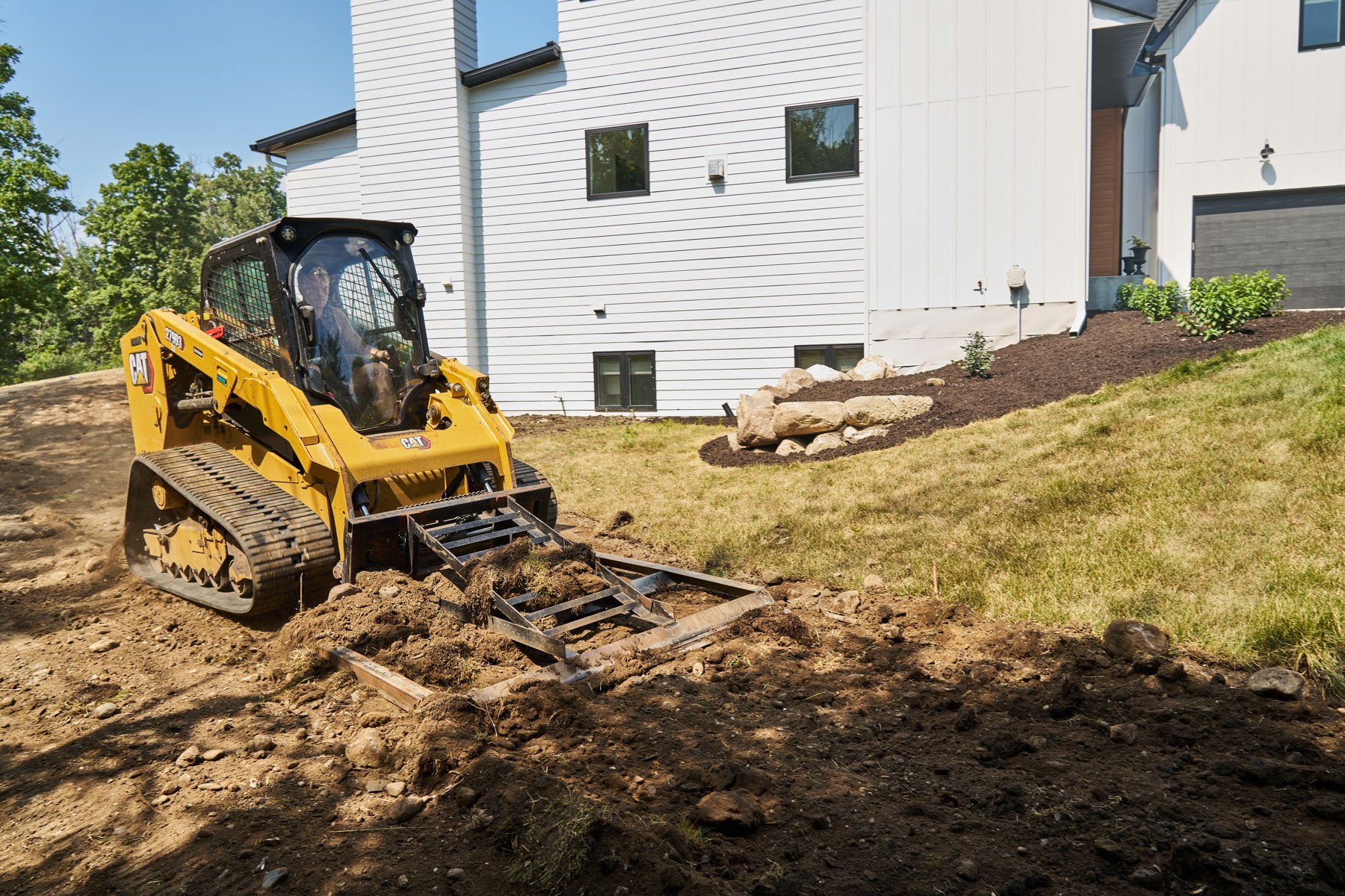 Yellow Cat skid steer grading a property in Wayzata
