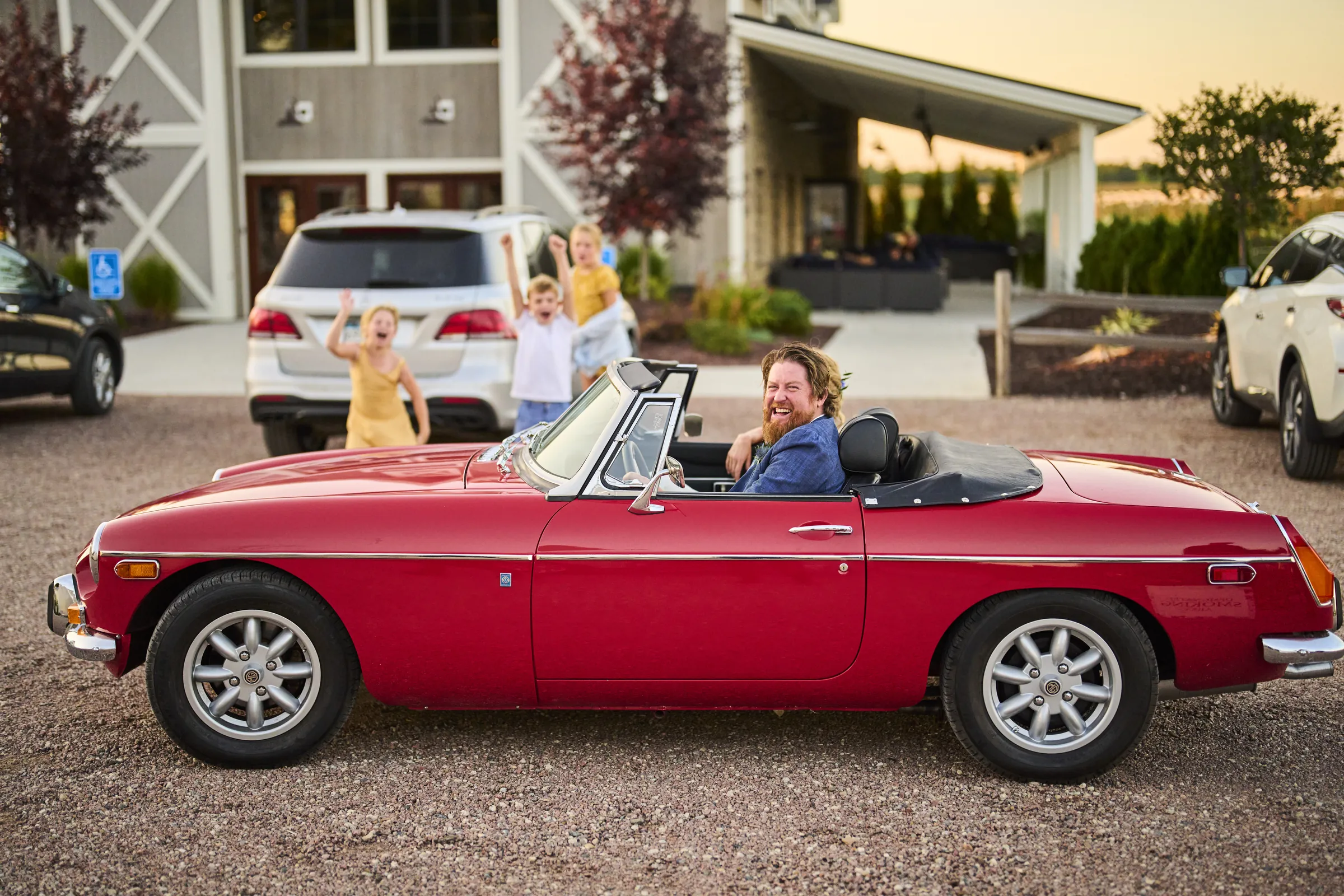 Jeanne and Brian sit in a red vintage convertible outside the barns at Ashery Lane Farm, Ashery Lane Farm, Mayer, Minnesota
