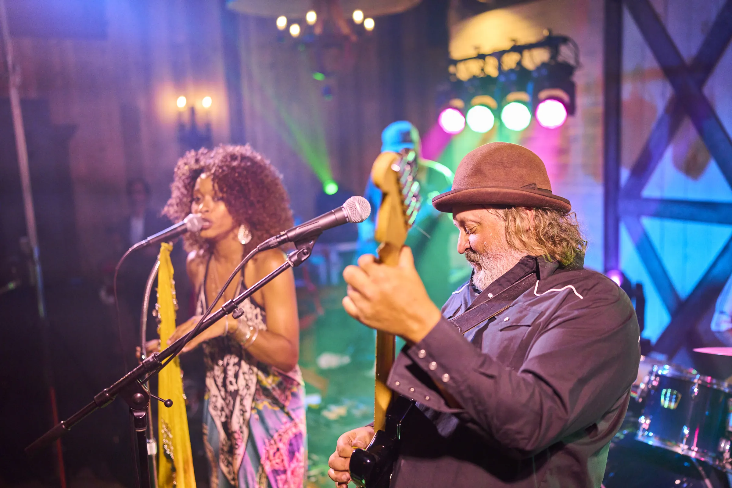 A singer and guitarist perform under colorful stage lights during Jeanne and Brian’s wedding reception, Ashery Lane Farm, Mayer, Minnesota