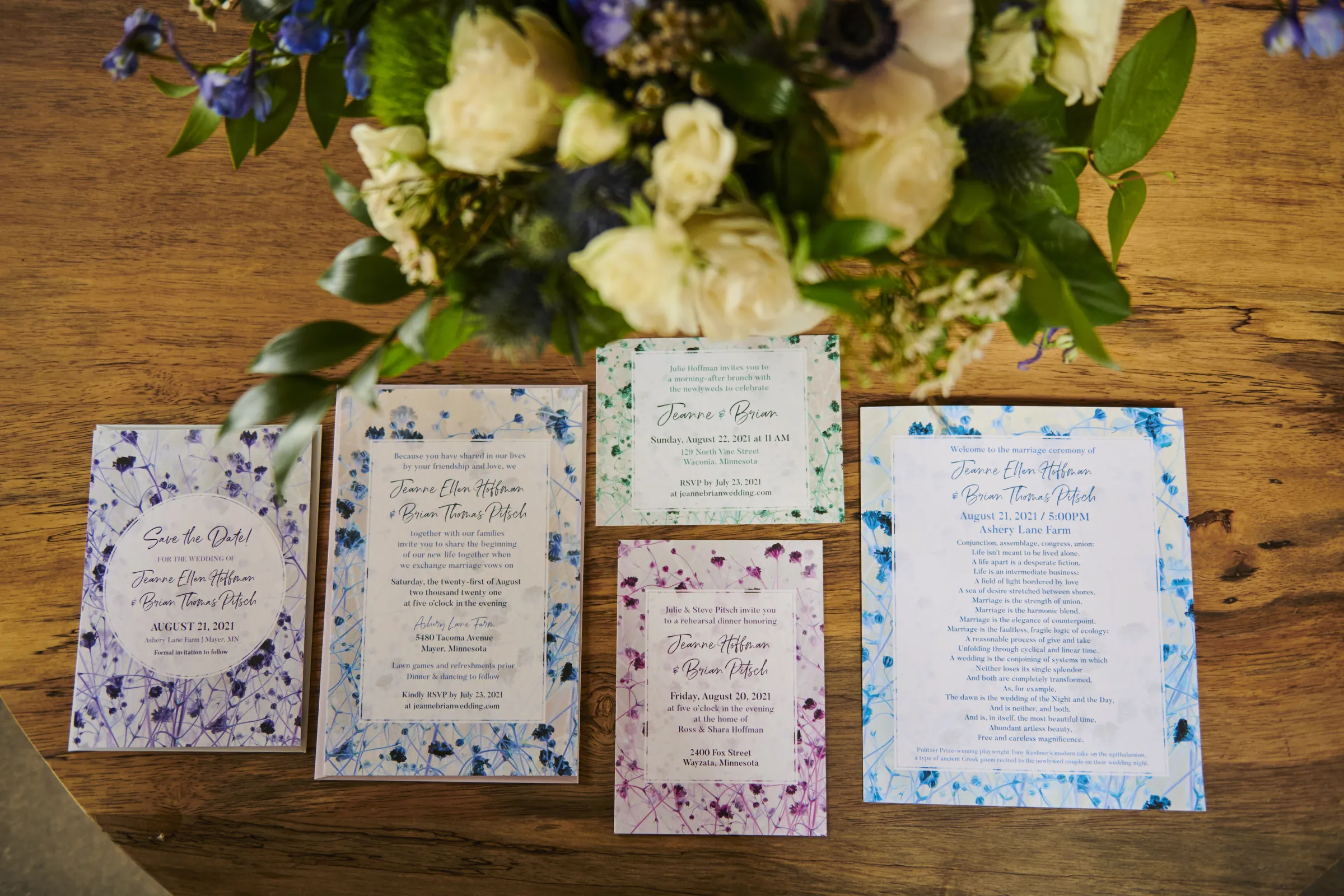 A spread of floral wedding stationery beneath a white and blue bouquet on a wooden table, Ashery Lane Farm, Mayer, Minnesota