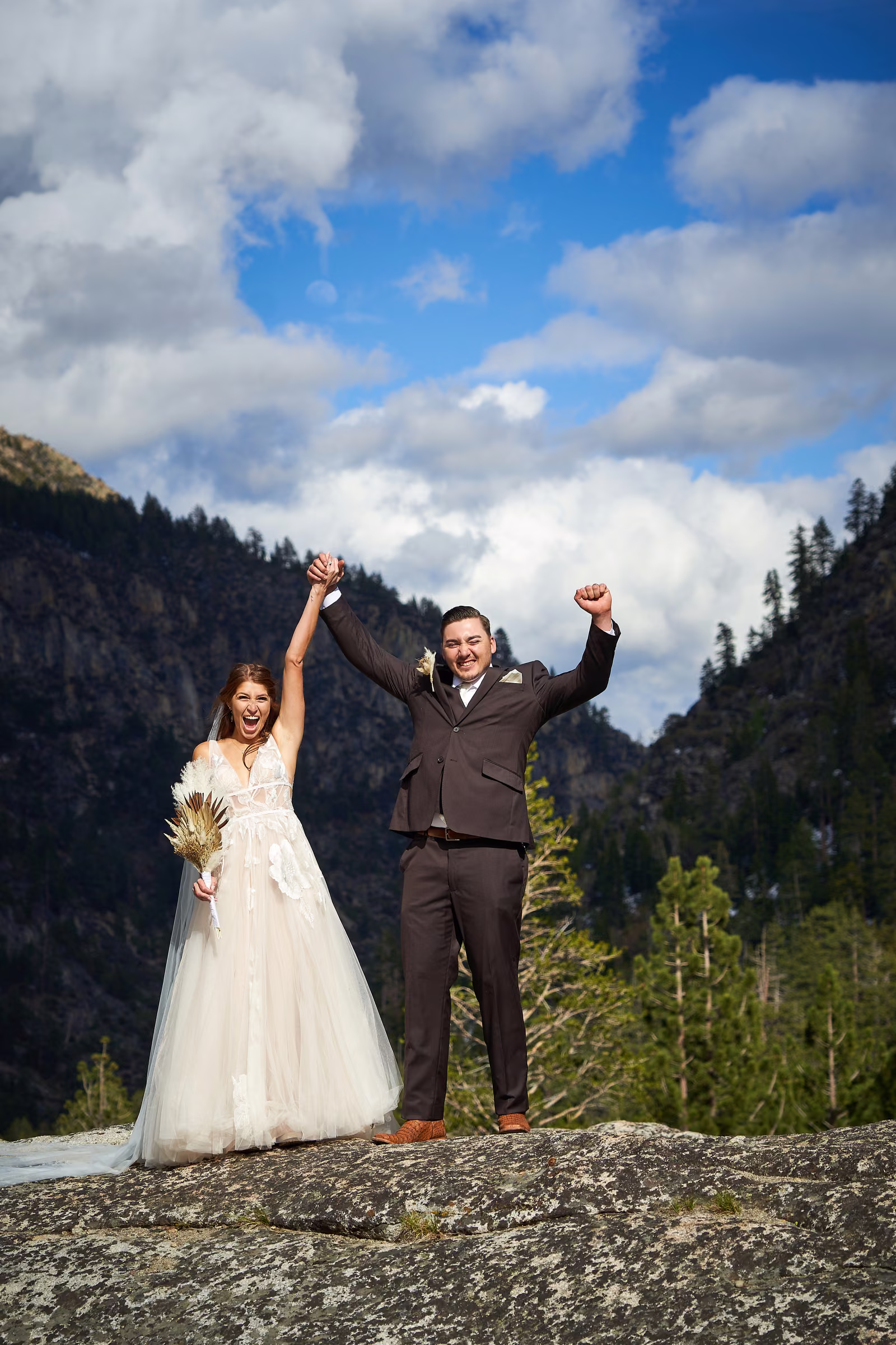 Joe and Gabby raise their joined hands in celebration above the mountain valley, Hope Valley, California