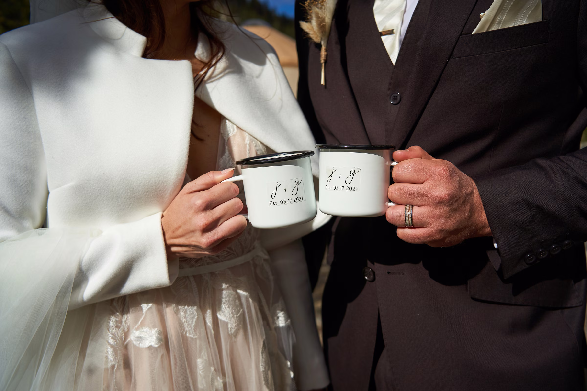 Joe and Gabby hold custom camp-style cups printed with their initials and wedding date, Hope Valley, California