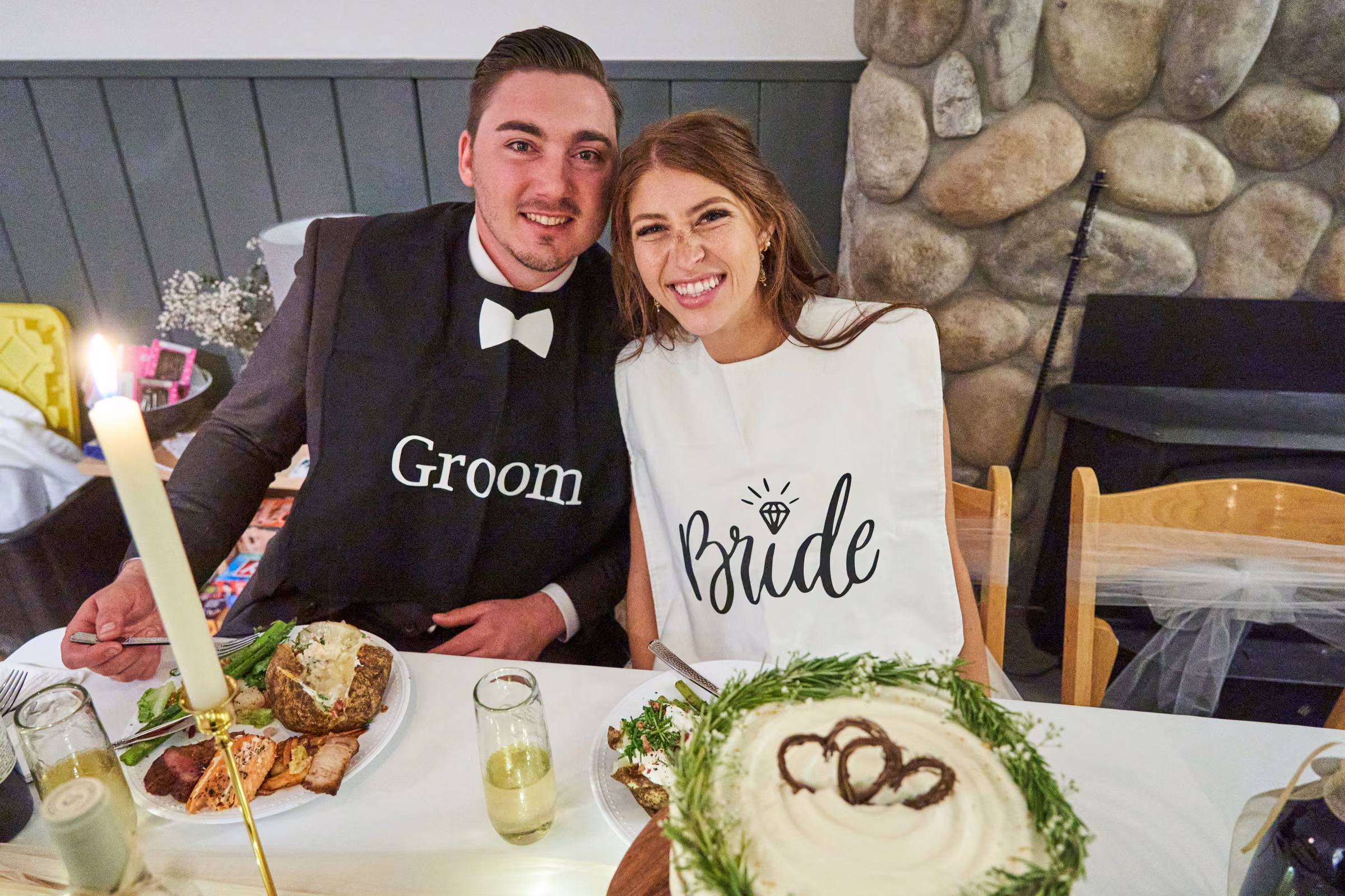 Joe and Gabby smile together at their reception table wearing matching Groom and Bride bibs, Hope Valley, California