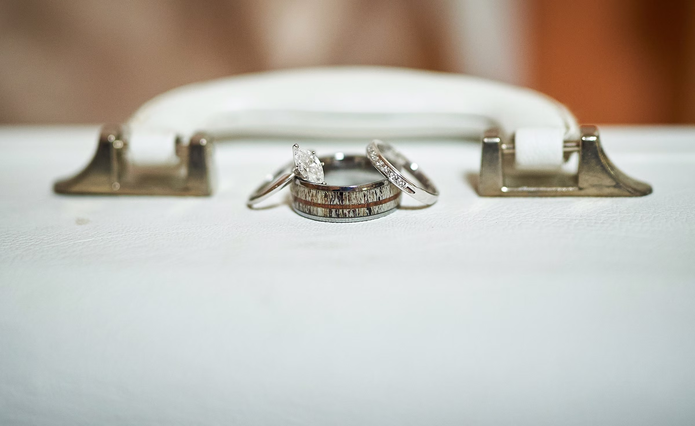 Wedding rings rest on a pale vintage suitcase beside its handle, Hope Valley, California