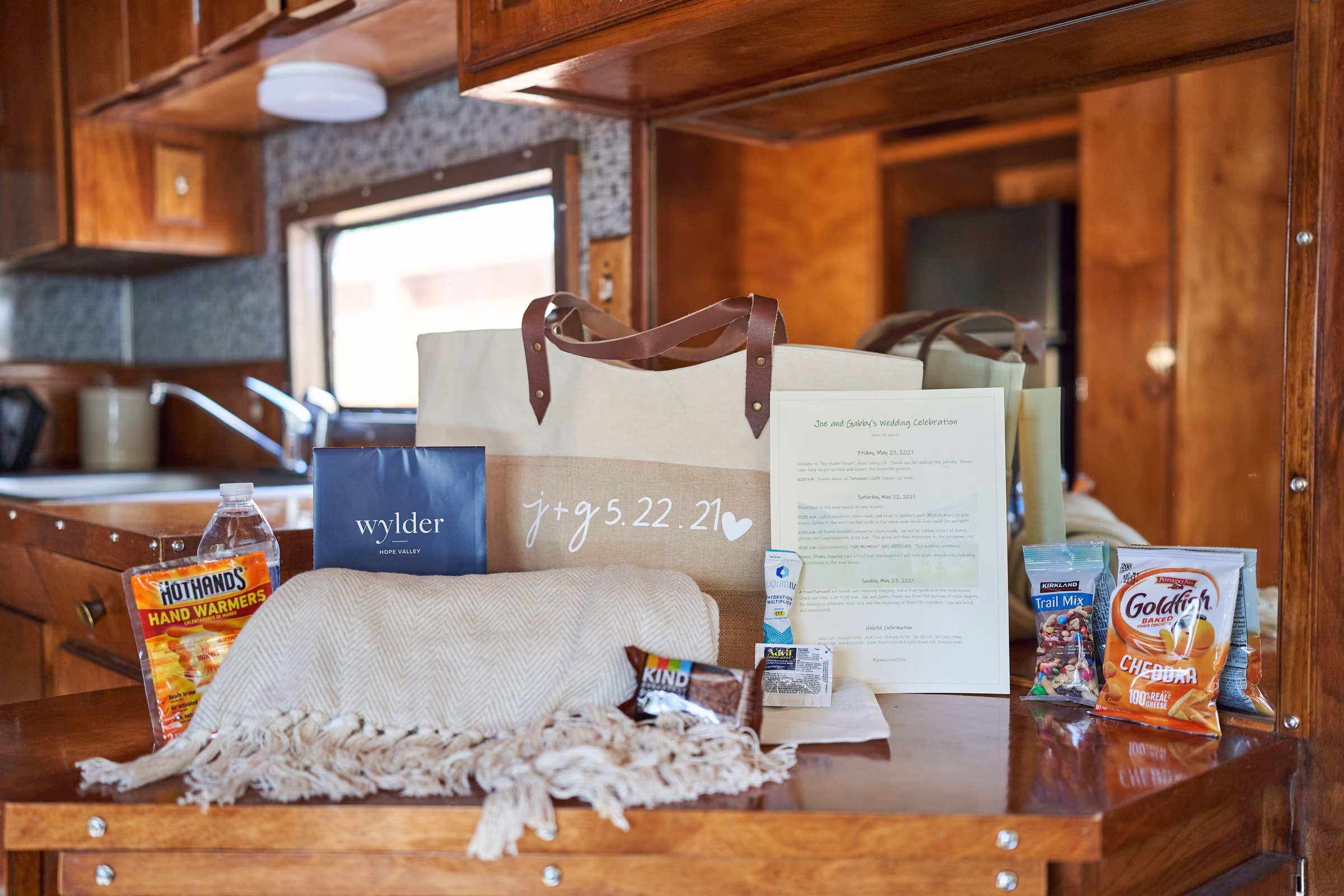 Joe and Gabby’s personalized wedding welcome bag, blanket, hand warmers, snacks, and weekend notes arranged inside the trailer, Hope Valley, California
