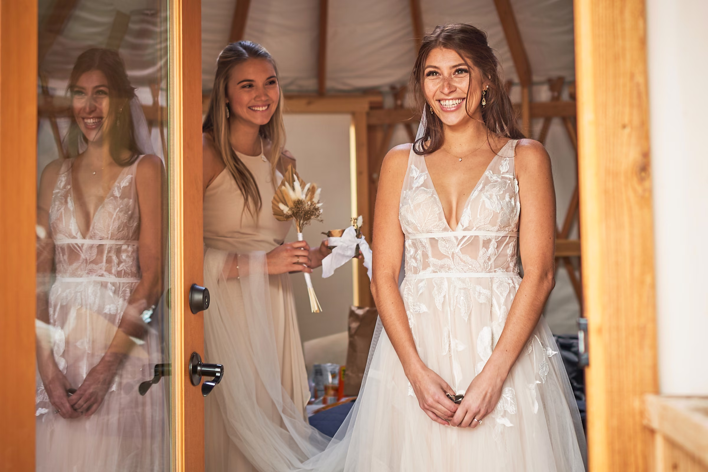Gabby smiles in her wedding dress at the open door of the yurt where she got ready, Hope Valley, California