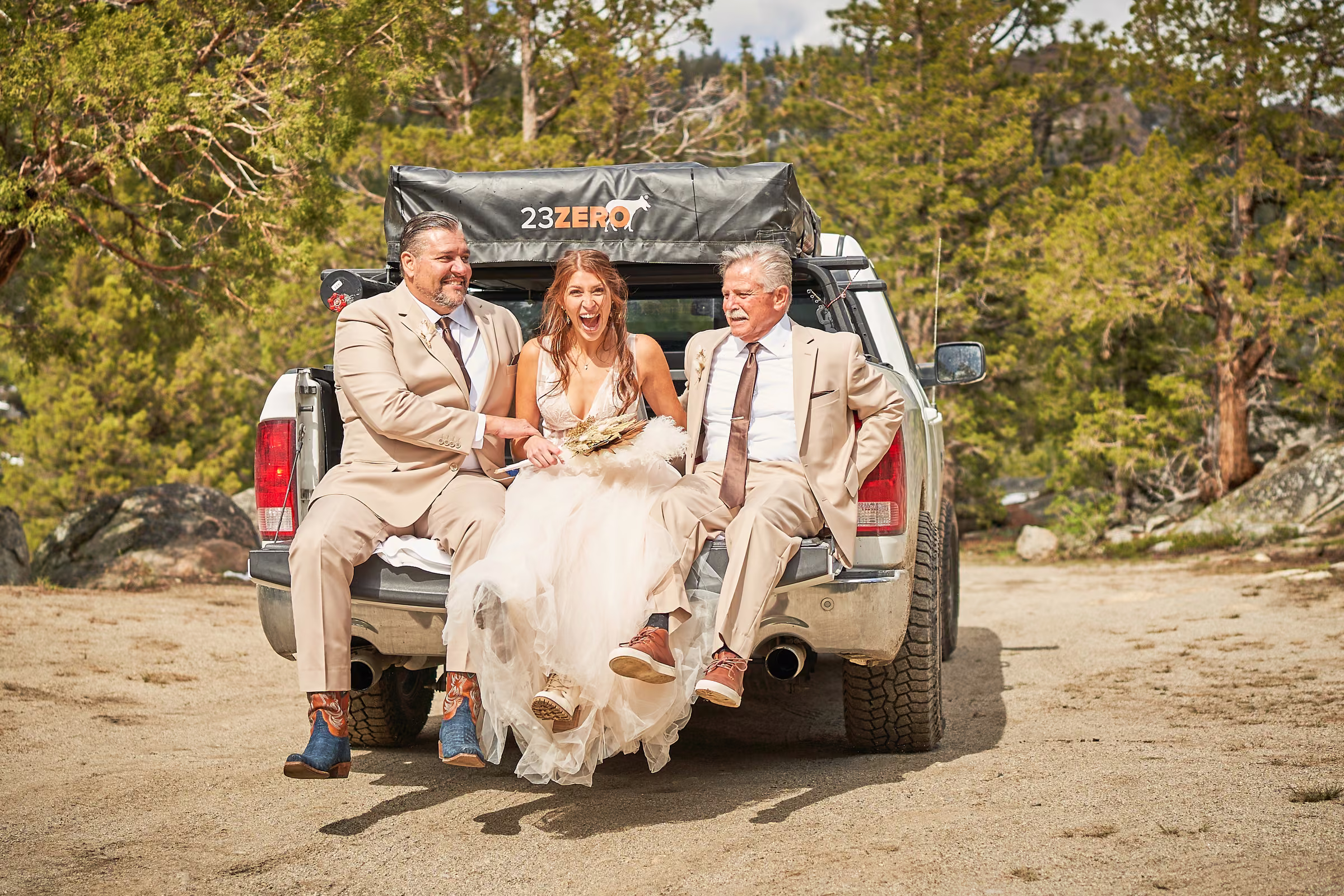 Gabby sits on the tailgate of a pickup truck between her father and stepfather on the way to the ceremony, Hope Valley, California