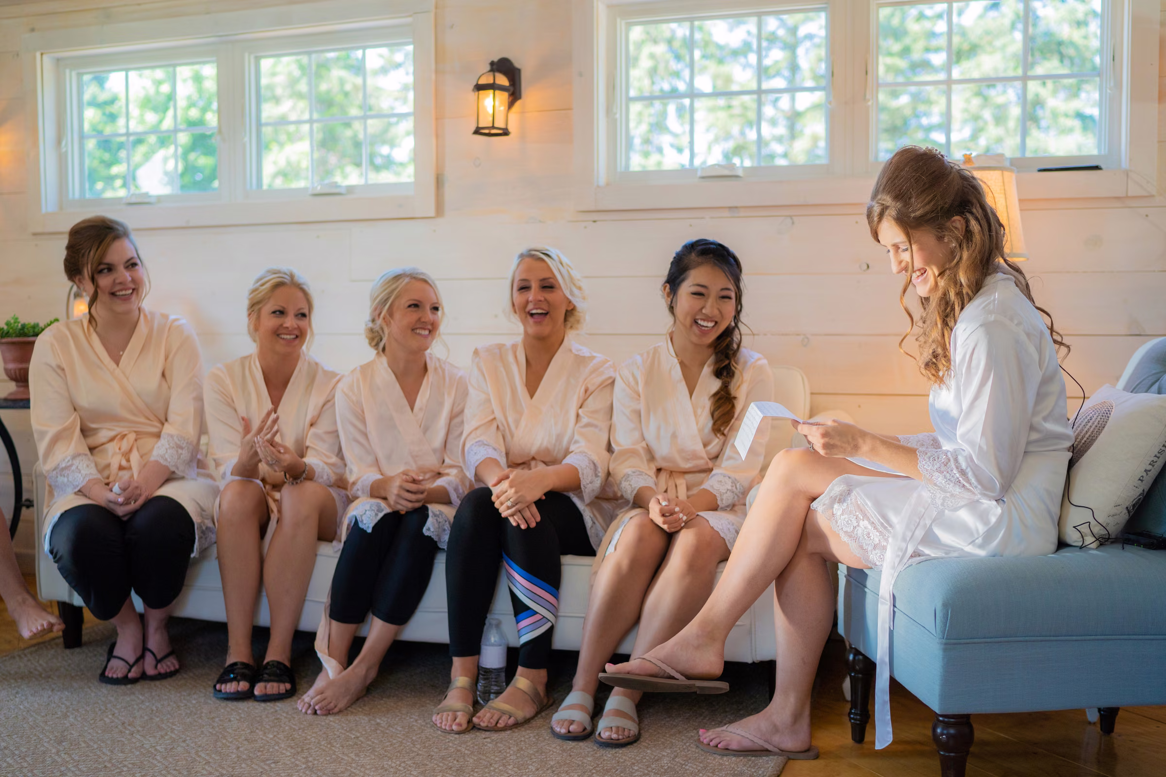 Katie reads a letter from Tobias while her bridesmaids sit beside her in their robes