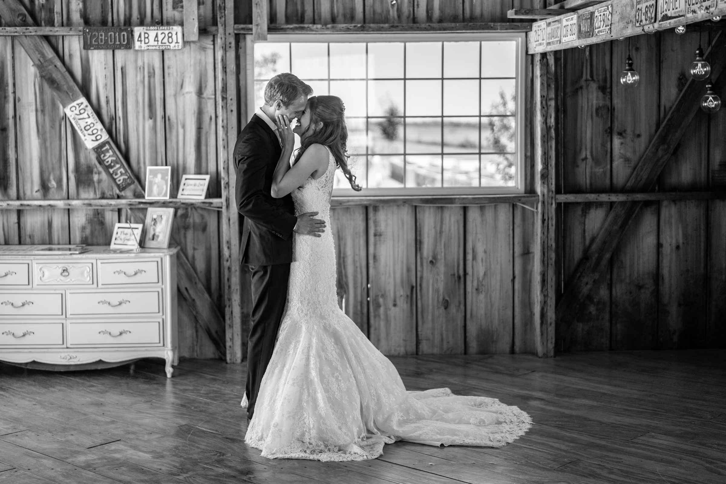 Katie and Tobias kiss beside a large barn window during their first look