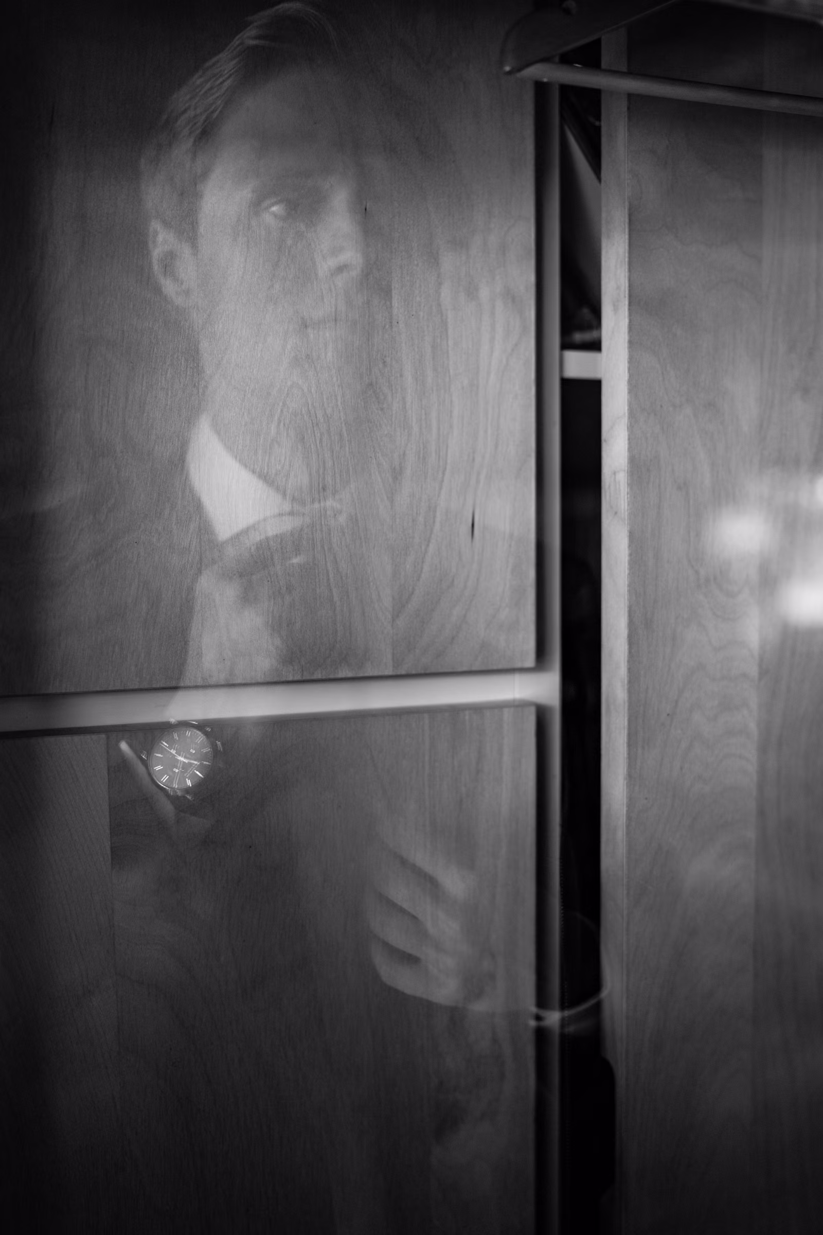 Black-and-white view of Tobias getting dressed through a window