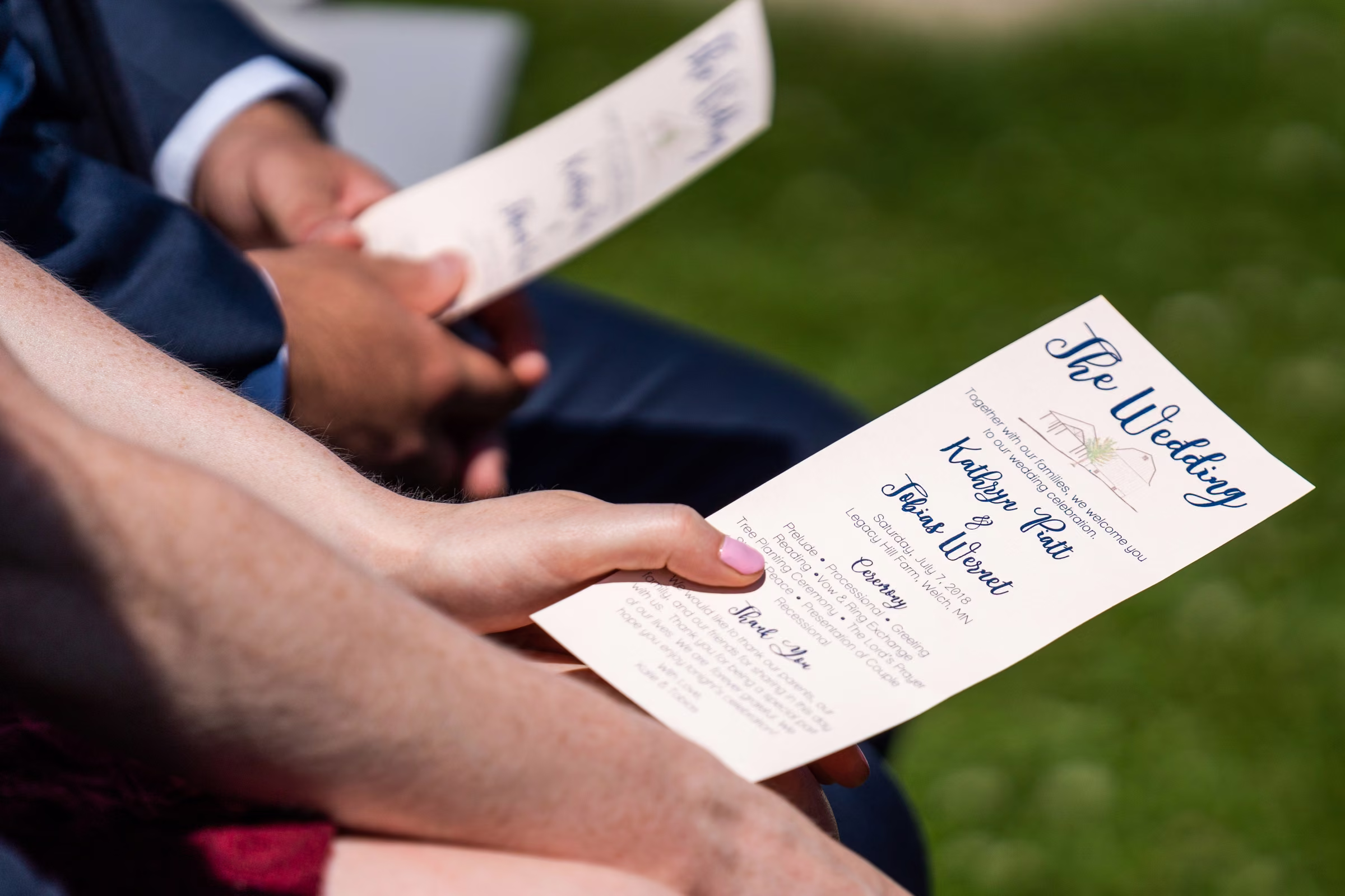 A guest holds Katie and Tobias’s wedding program during the ceremony