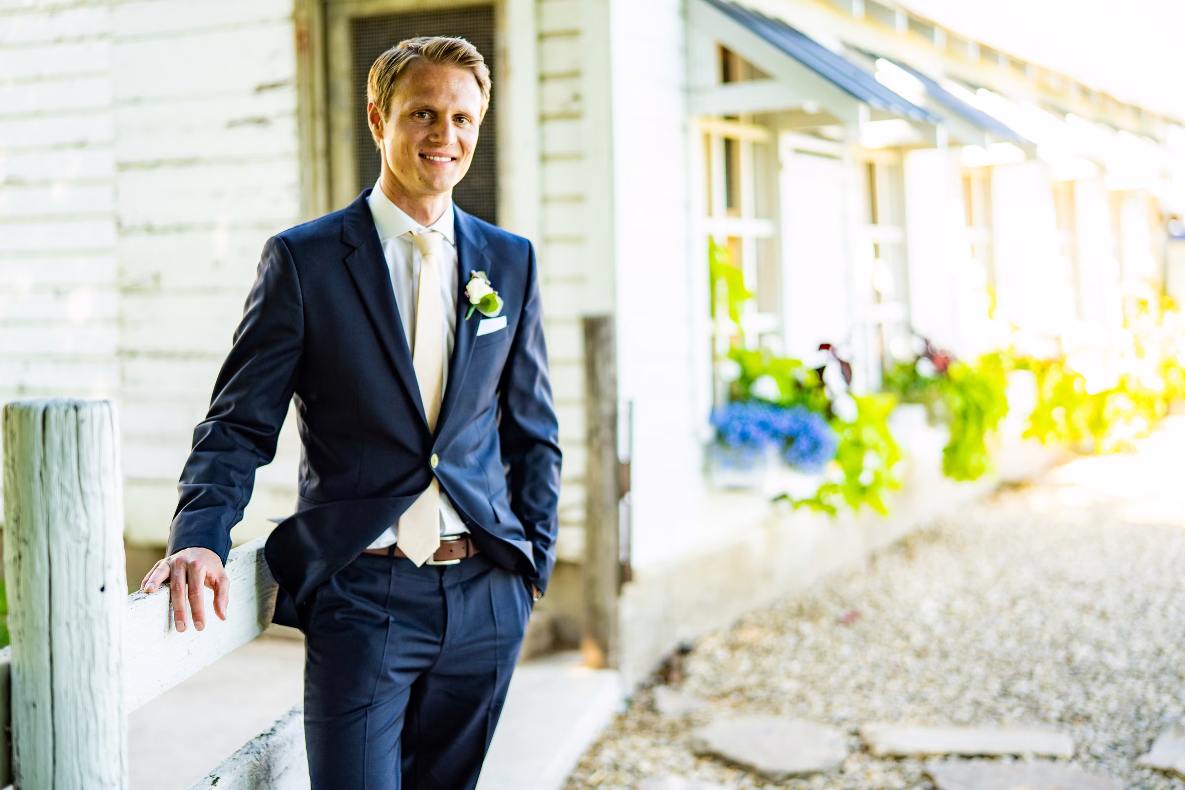 Tobias stands beside weathered white siding and windows at the farm