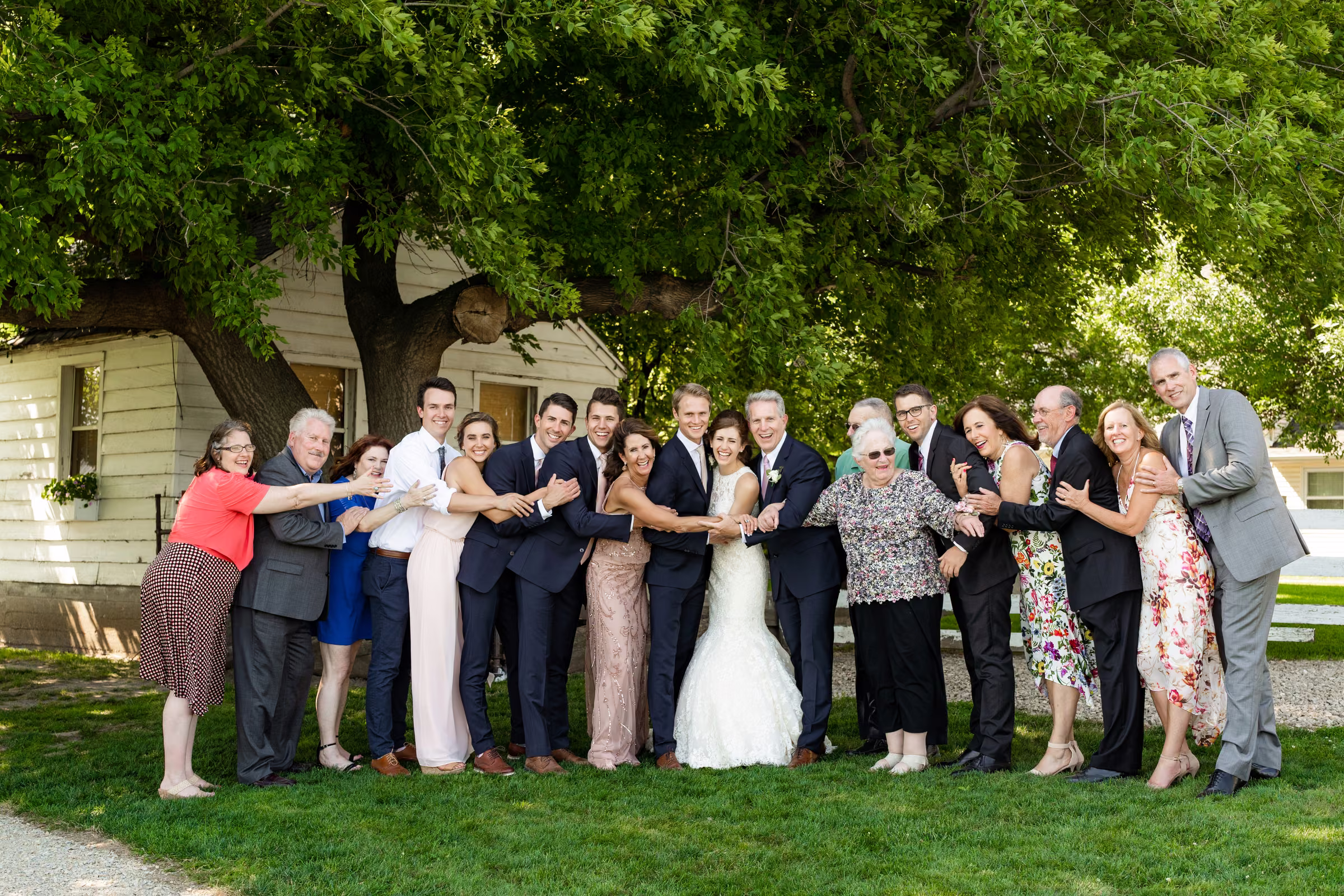 Katie and Tobias gather with family beneath a tree for a playful group photograph