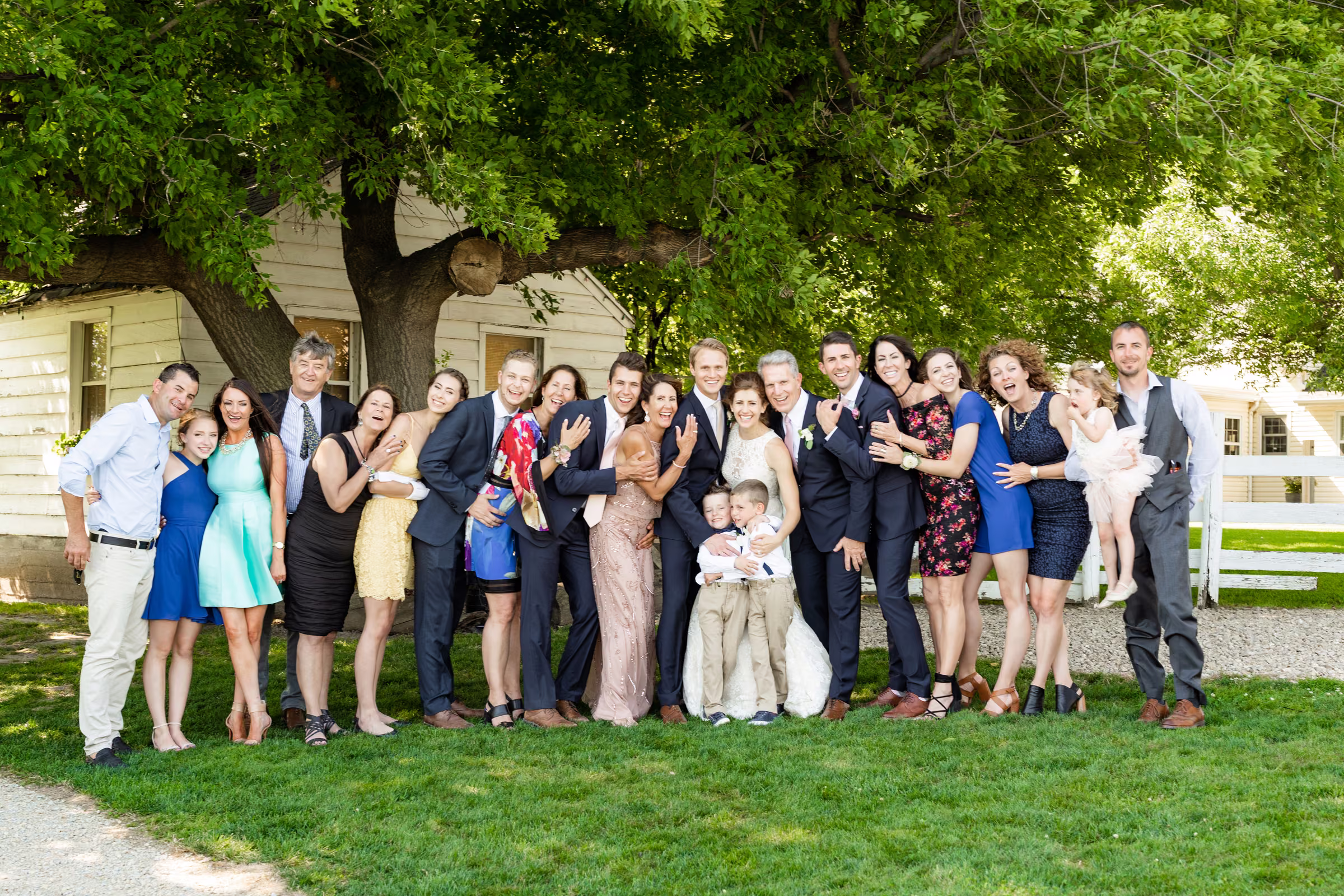 A large family group leans together around Katie and Tobias on the lawn