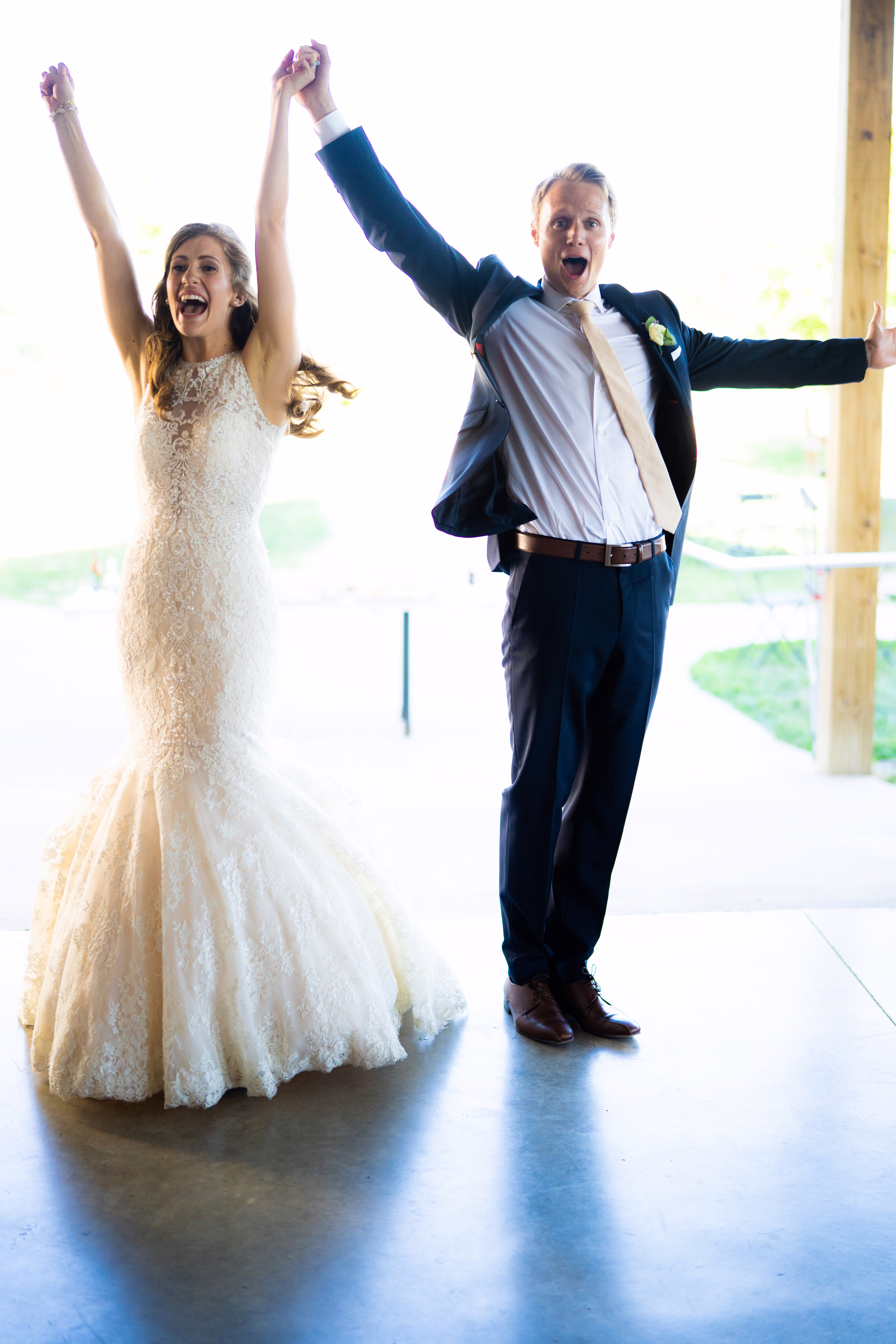 Katie and Tobias enter their reception with their arms raised in celebration
