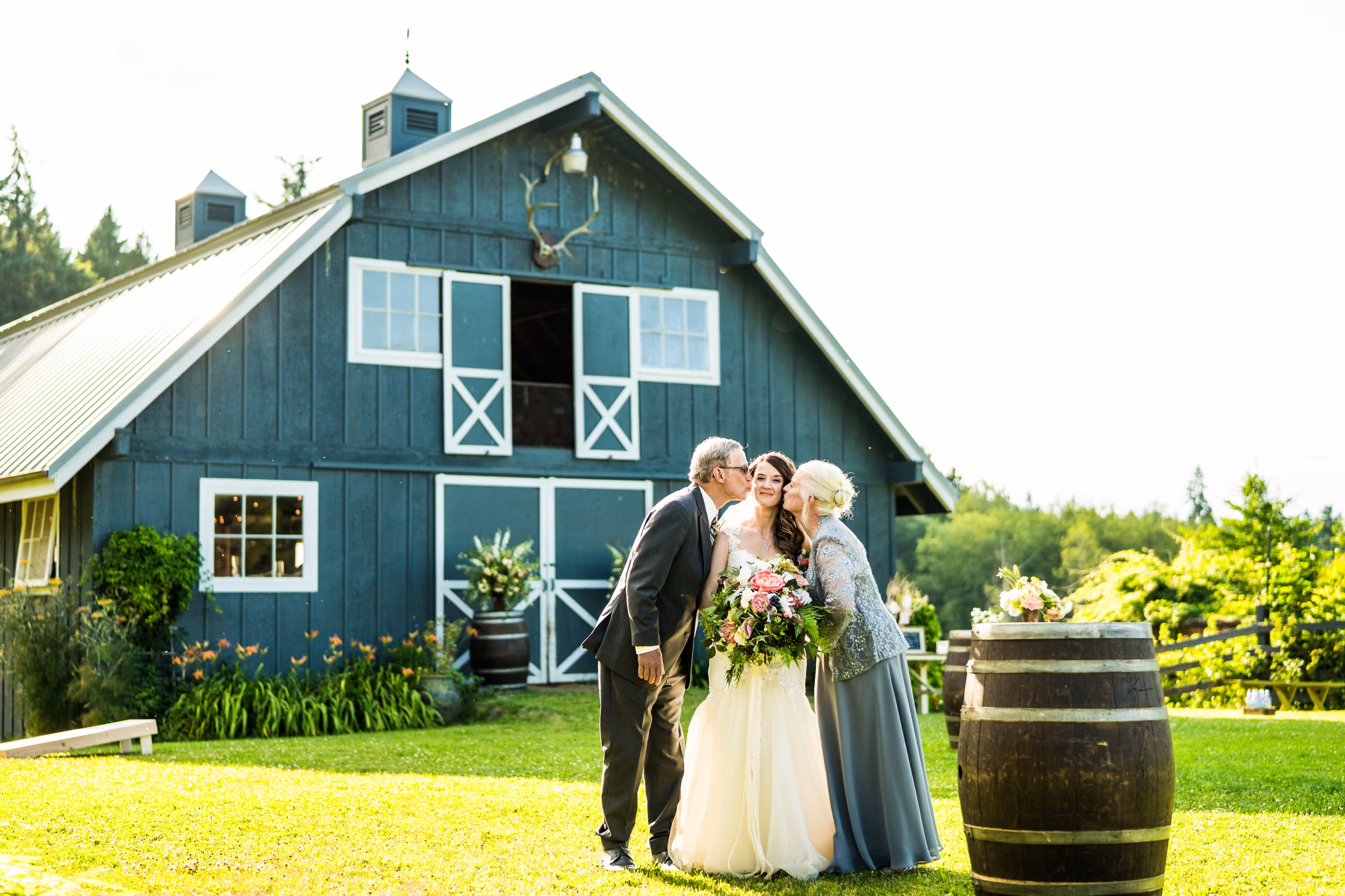 Kohleen stands with her parents beside the blue barn before the ceremony