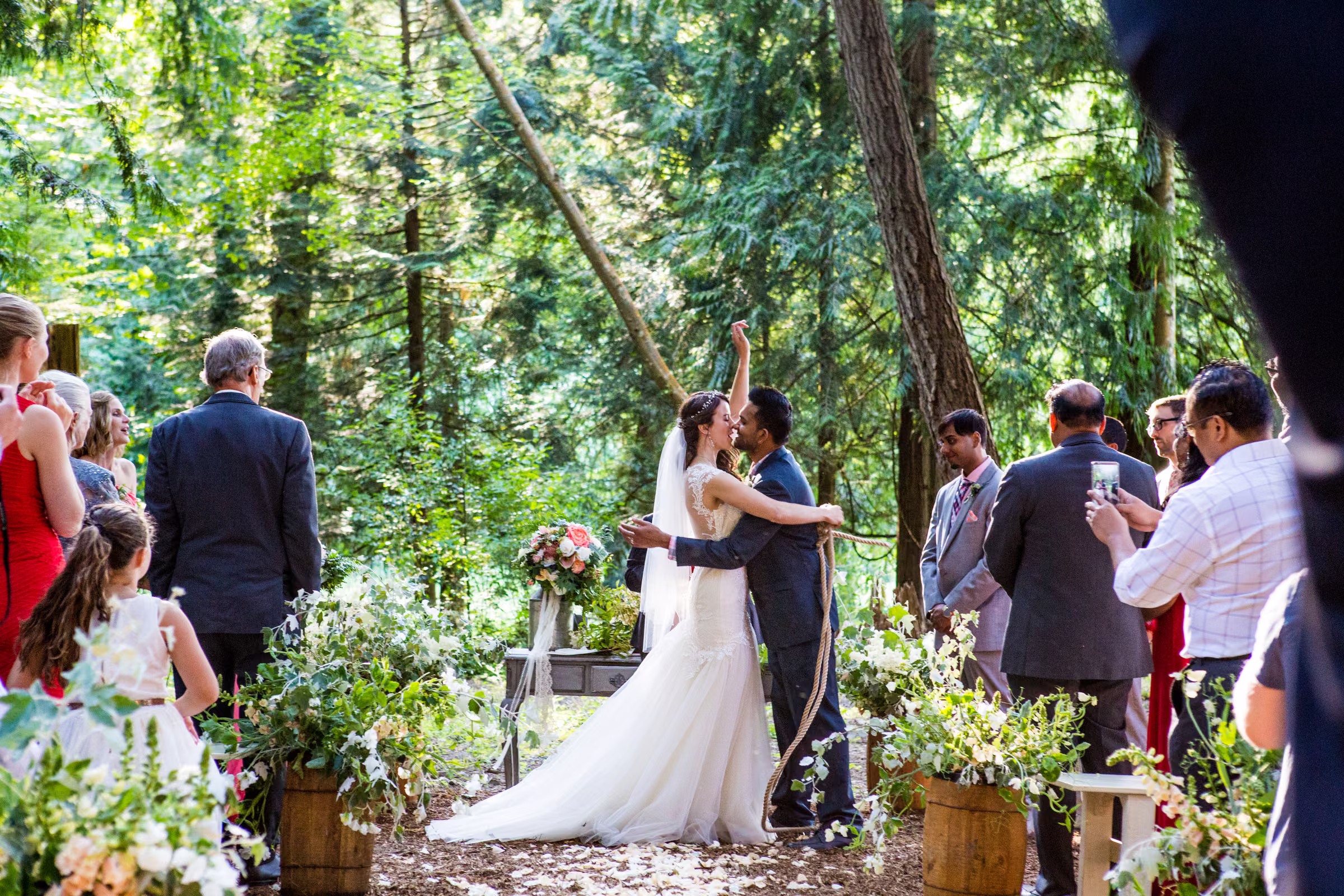 Kohleen and Kash kiss beneath the trees while guests look on