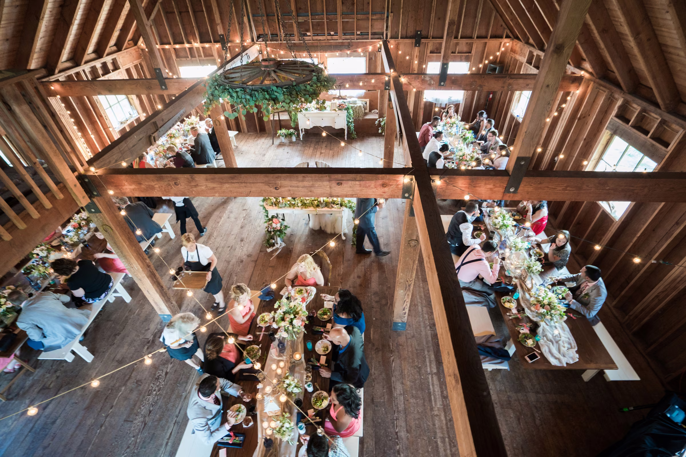 An overhead view from the barn loft shows guests seated at long reception tables
