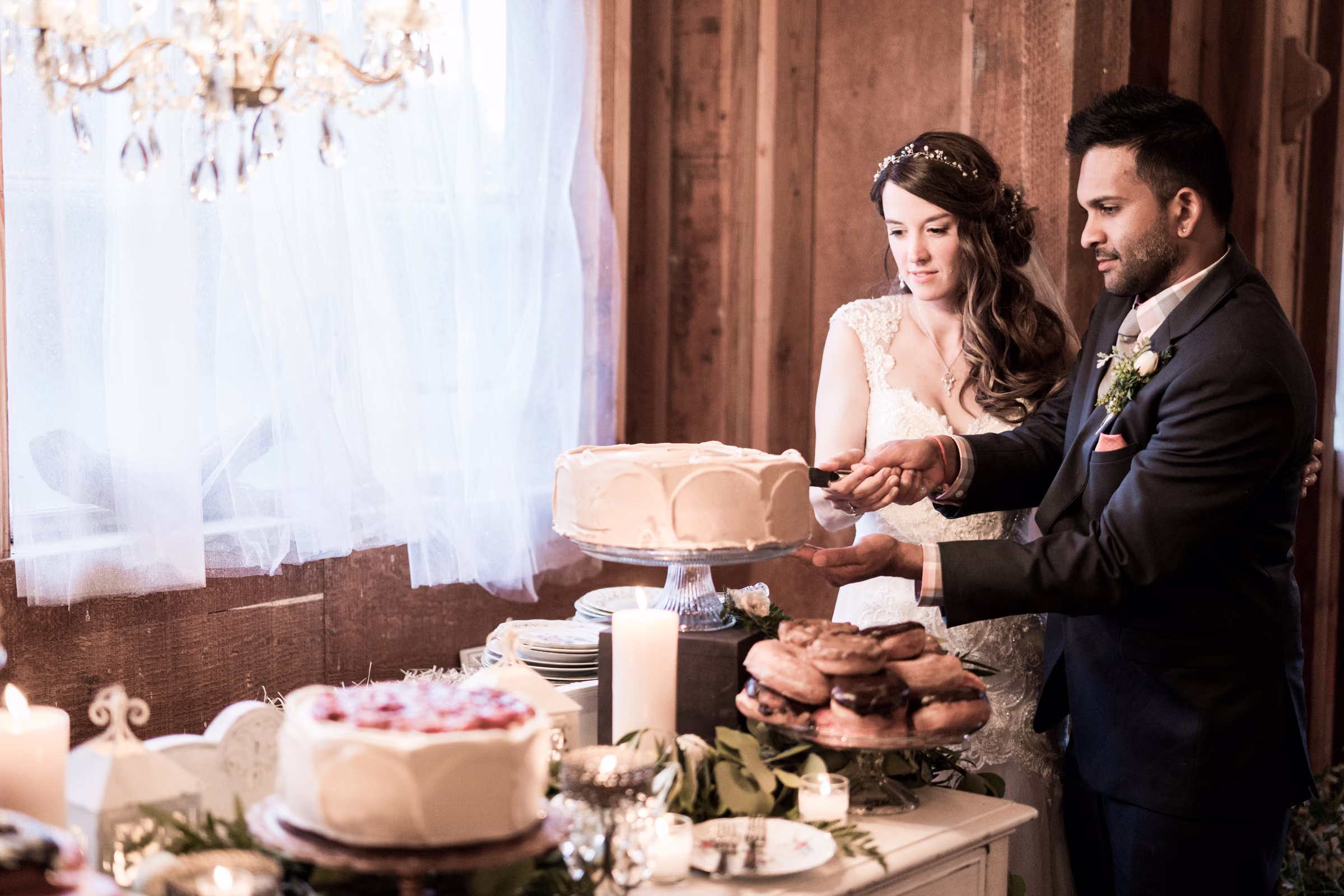 Kohleen and Kash cut their wedding cake together inside the barn