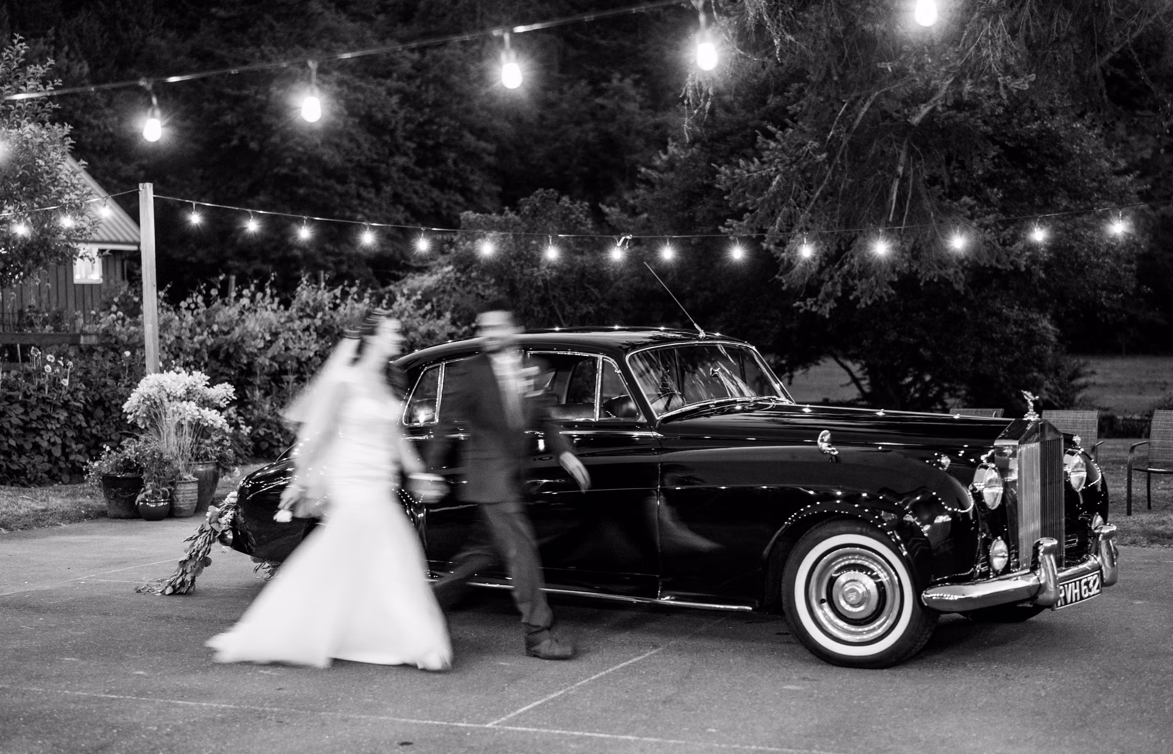 Kohleen and Kash pass a vintage Rolls-Royce in an intentionally blurred black and white photograph