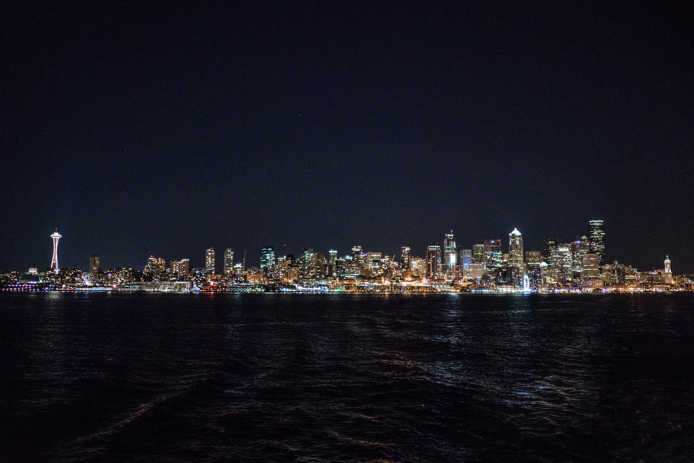 The illuminated Seattle skyline stretches across dark water at night