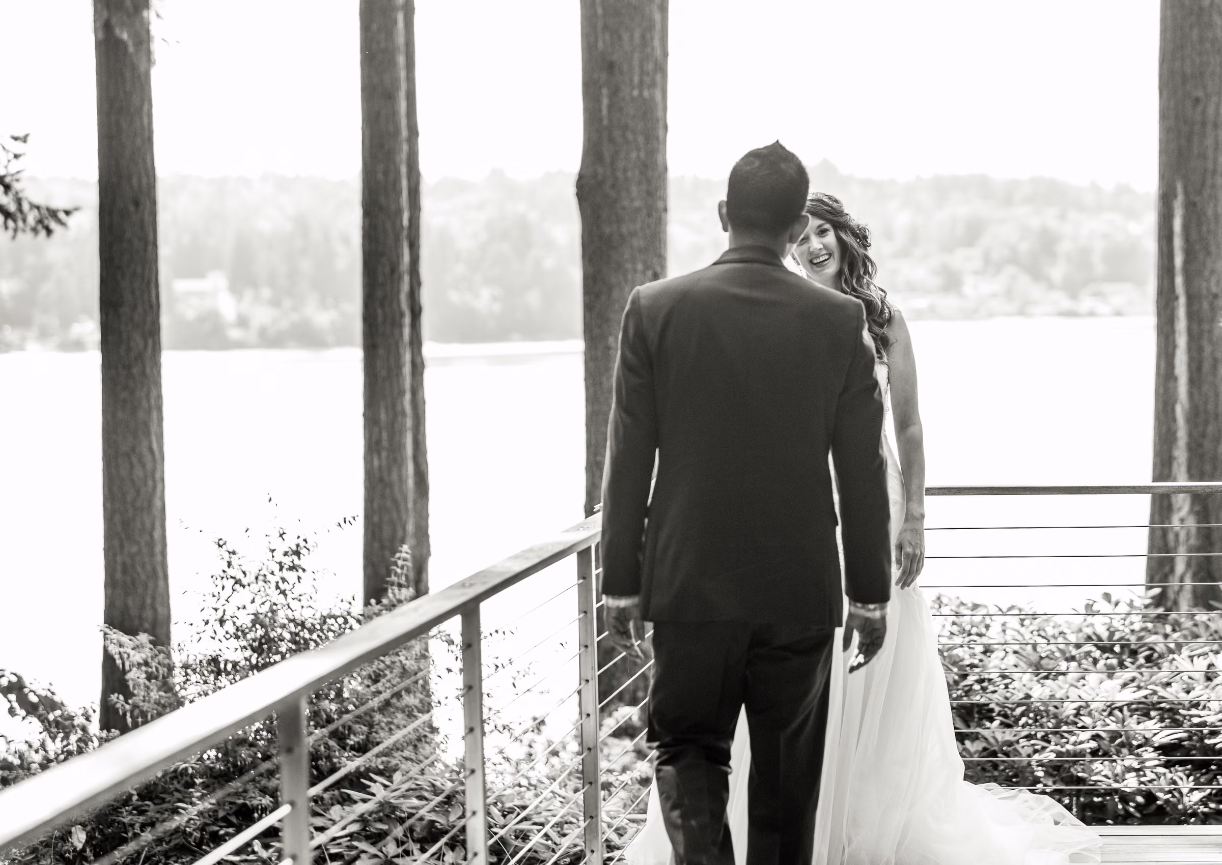 Kash turns toward Kohleen for their first look among tall trees beside the water