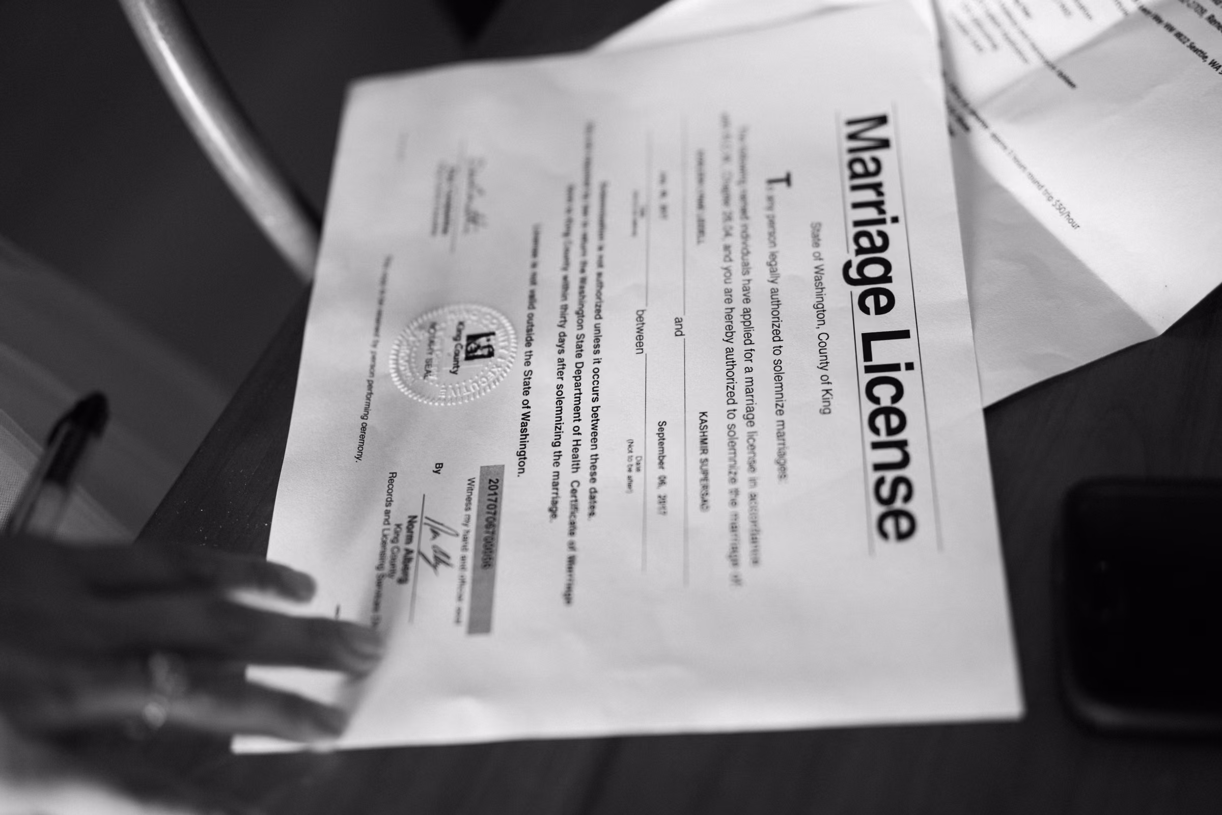 A close black and white photograph of the couple’s marriage license as it is signed